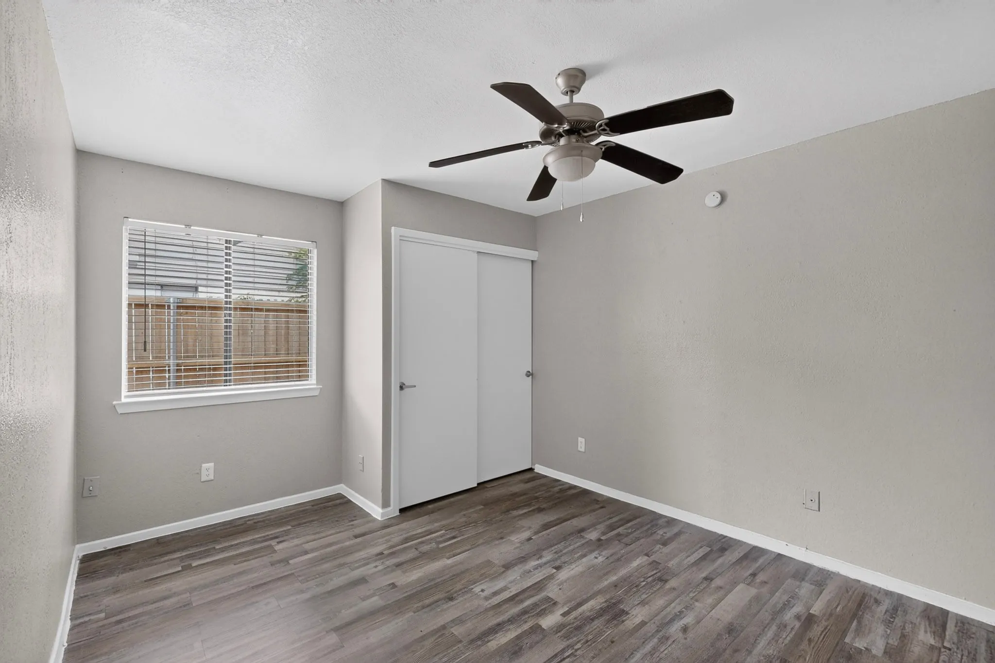 Spacious room featuring wood-finish flooring, light gray wall paint, and white baseboards