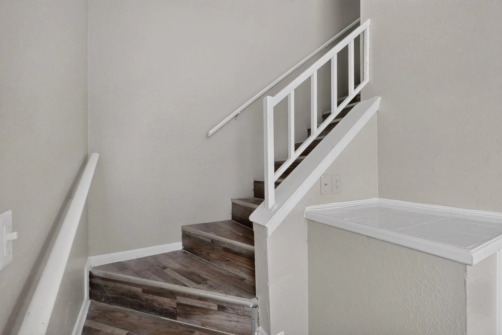 Interior staircase featuring wood-finish treads and risers, white painted balusters, and a matching handrail