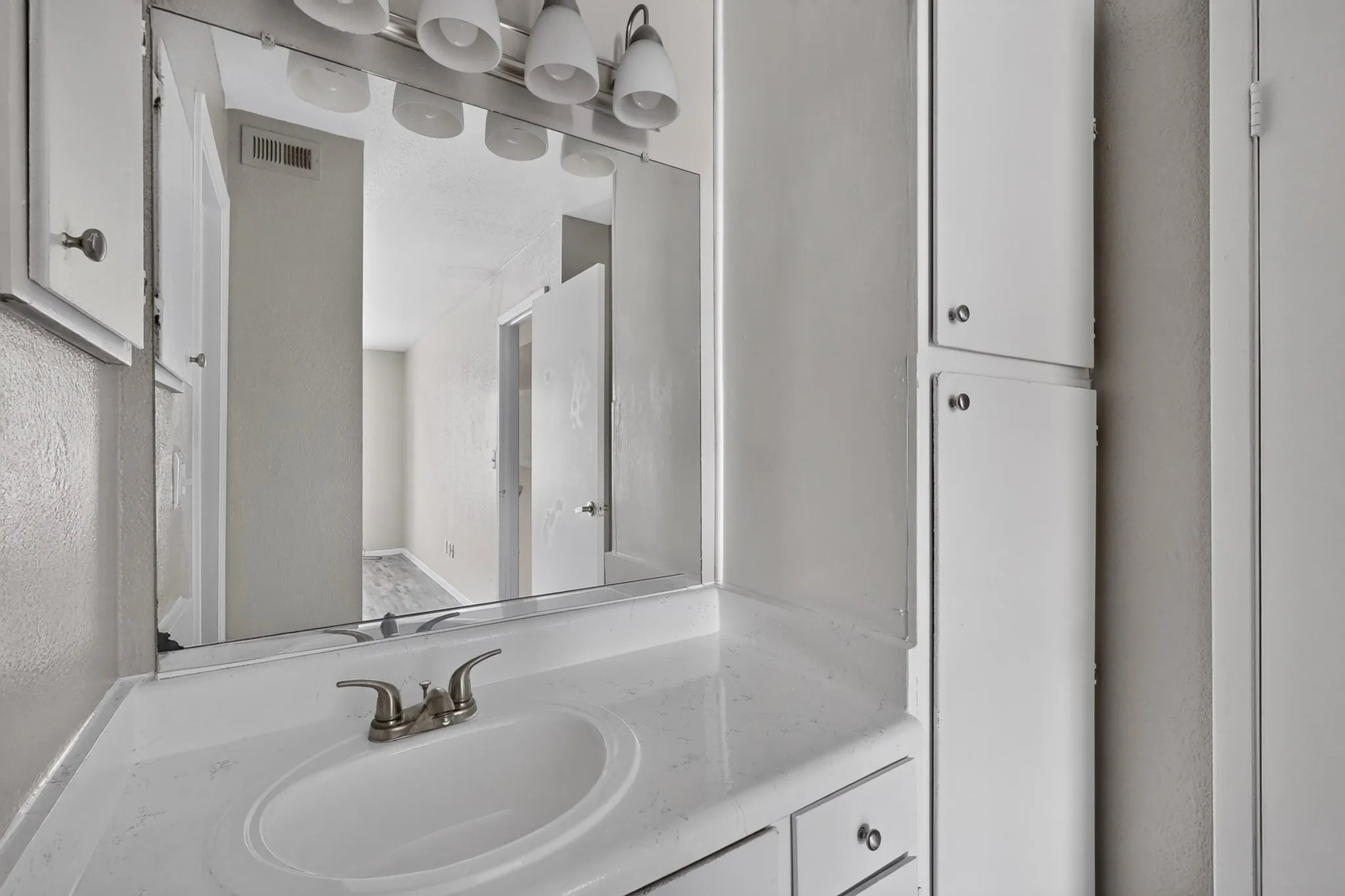 Bathroom vanity with an integrated sink, brushed nickel faucet, and a large wall-mounted mirror
