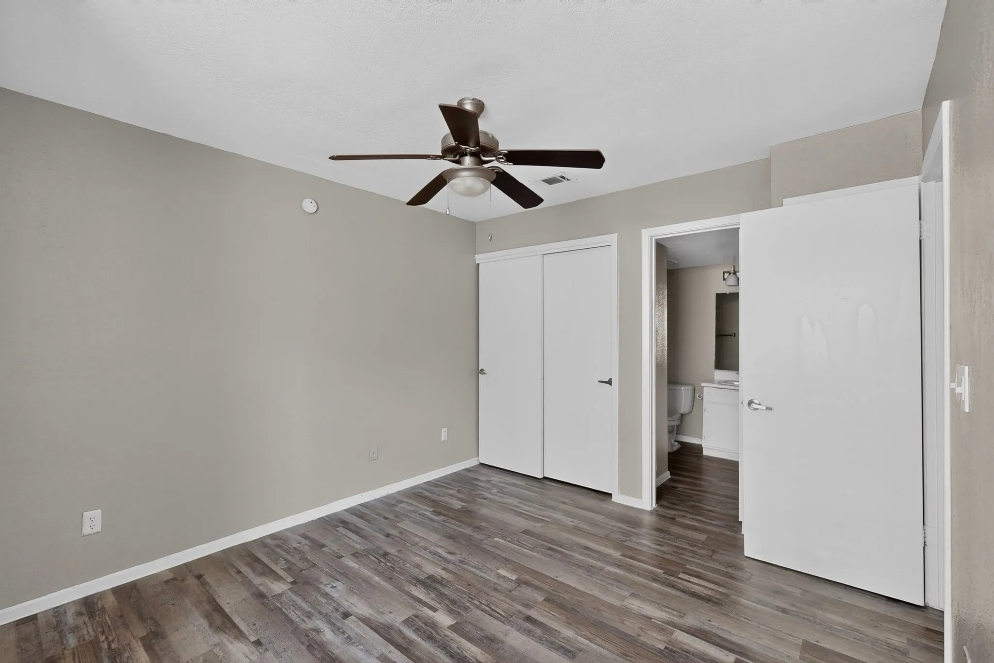 Room with wood-finish flooring, neutral wall paint, and white trim
