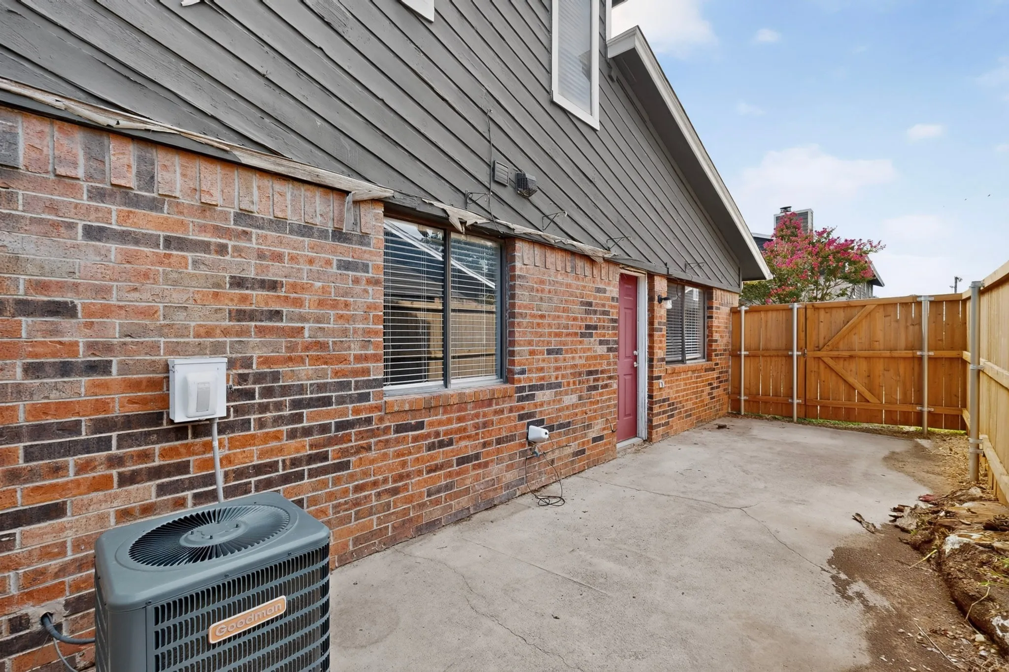Brick exterior featuring a private concrete patio, solid wood fencing, and an HVAC unit