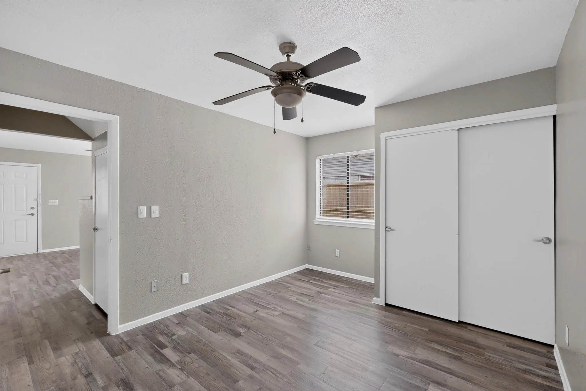 Bedroom featuring wood-finish flooring, a ceiling fan, and a window with horizontal blinds