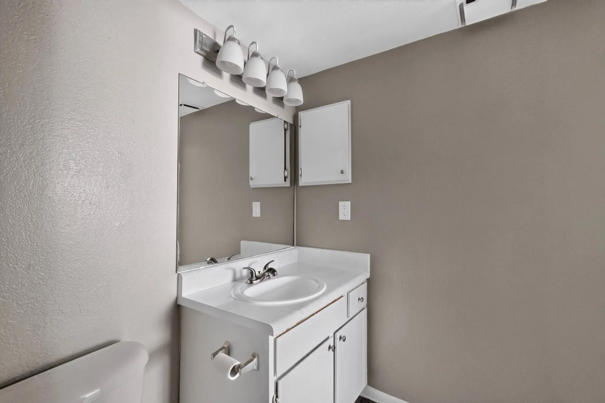 Bathroom vanity featuring a white countertop with an integrated sink, polished chrome faucet, and white cabinetry