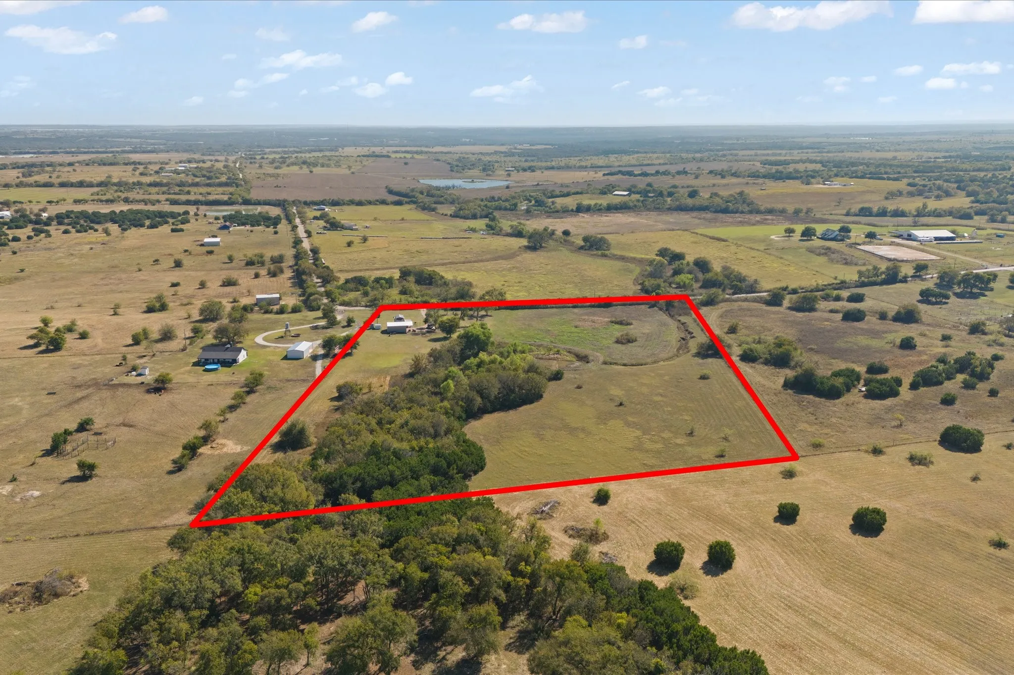 Expansive property featuring a mix of open fields, mature tree lines, and distant natural water features