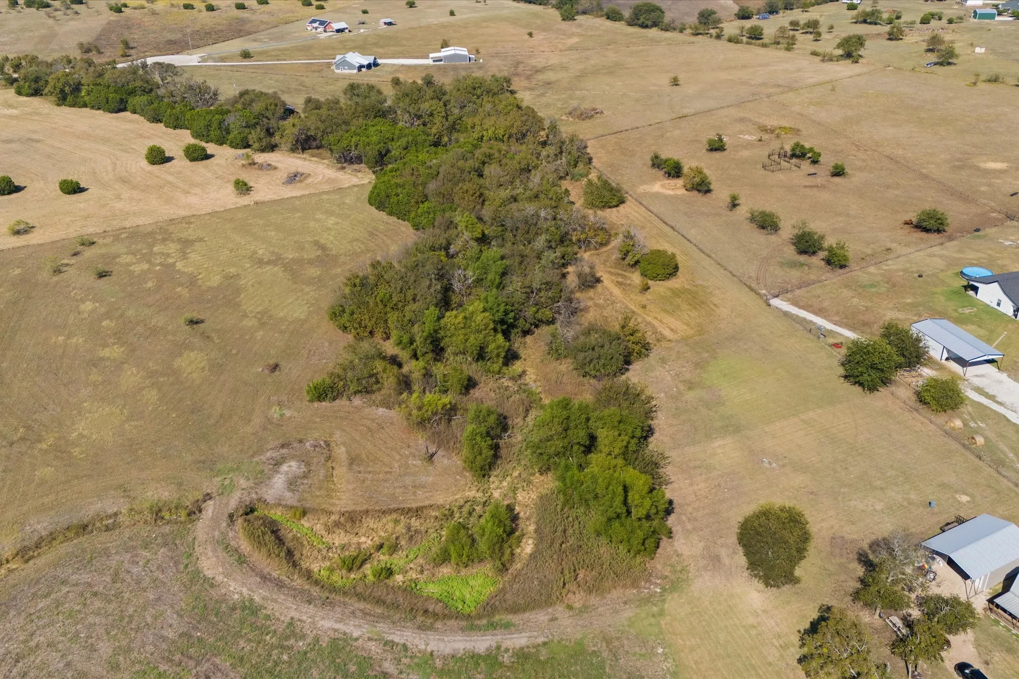 Expansive land parcel featuring open fields, scattered mature trees, and natural wooded areas