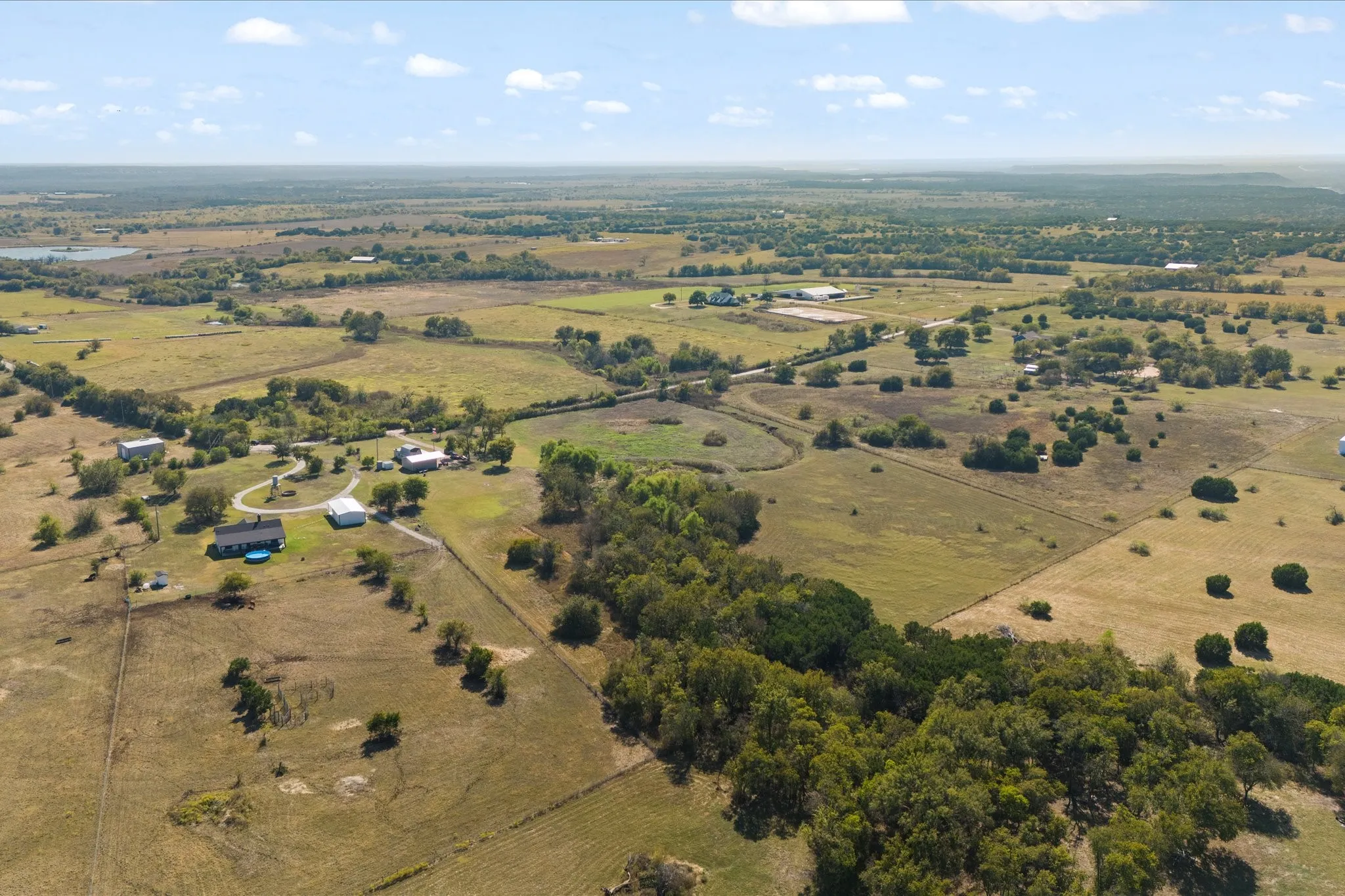 Expansive rural landscape featuring scattered residential structures, mature trees, and agricultural fields