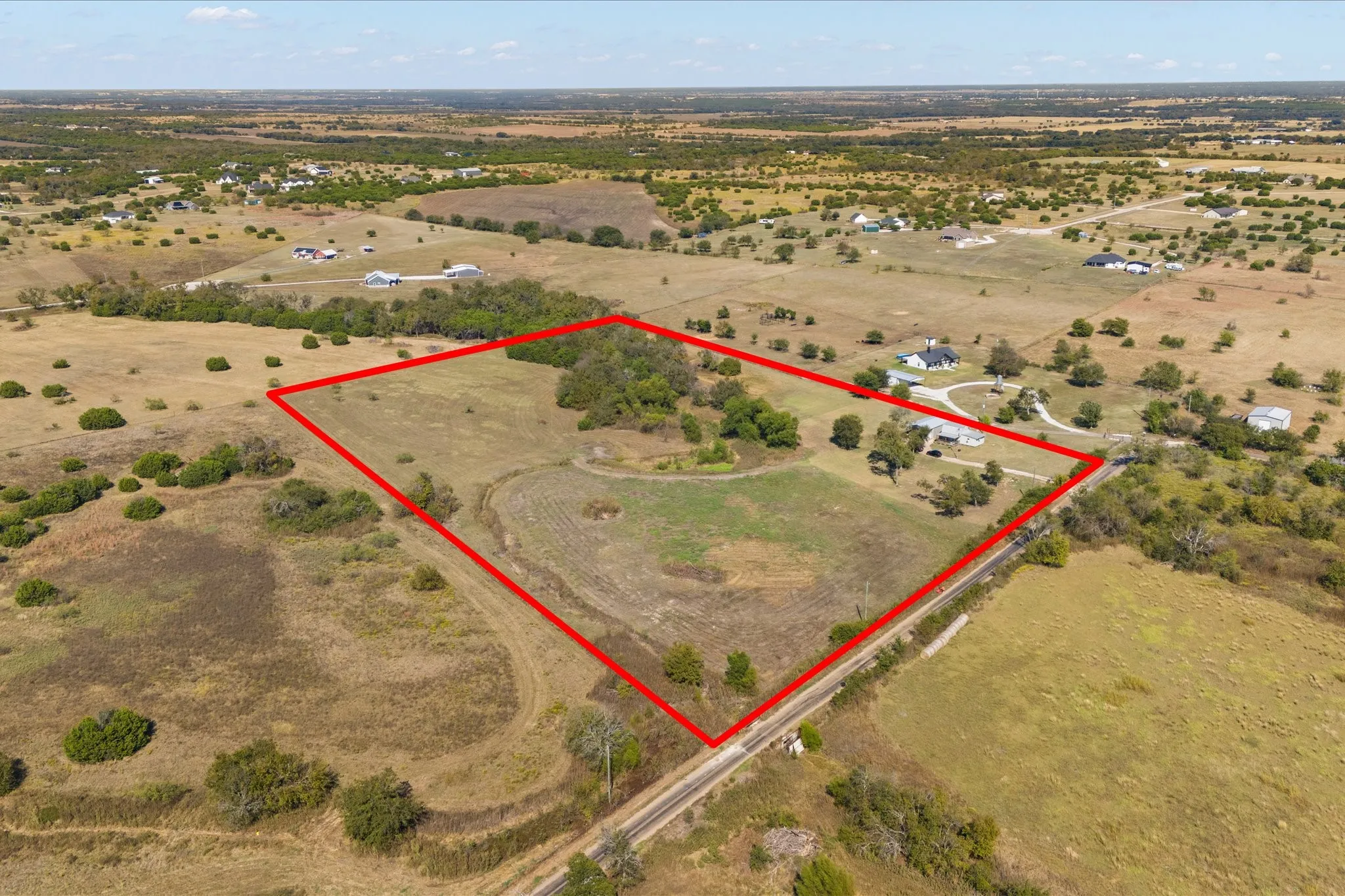 Expansive rural land parcel featuring varied terrain, scattered trees, open clearings, and perimeter marking