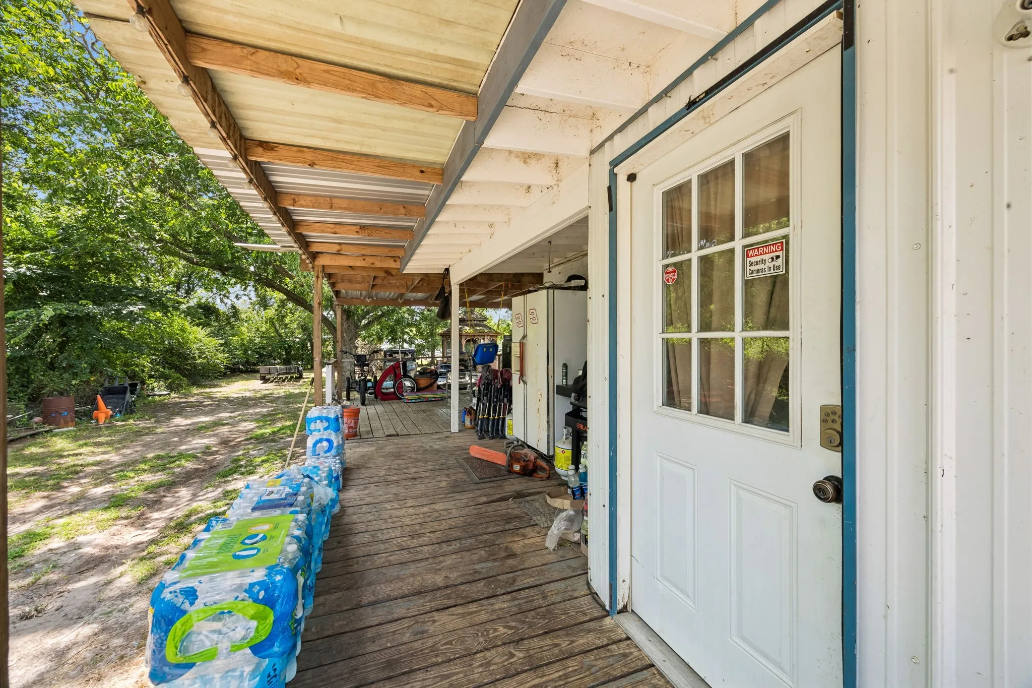 Covered porch featuring a wood-plank floor and a white exterior door with a multi-pane window