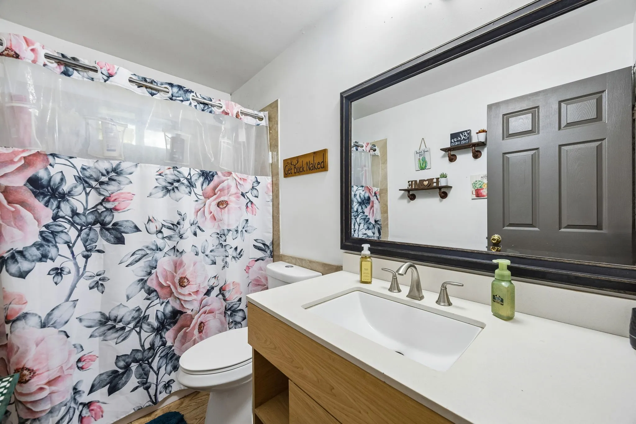 Bathroom featuring a light wood-finish vanity with a rectangular undermount sink, a wide framed mirror, and a white toilet