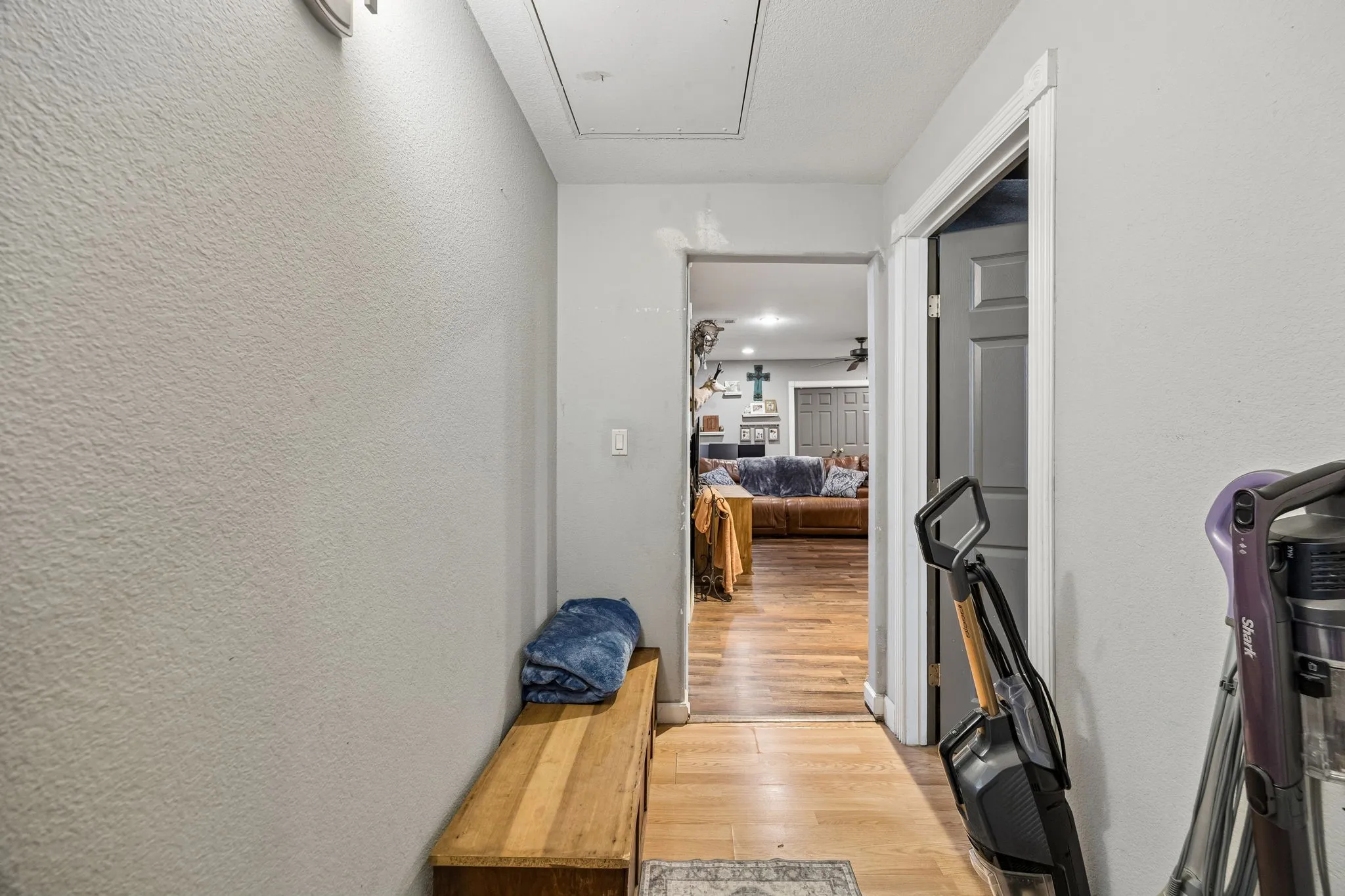 Hallway featuring light gray walls, white trim, and wood-finish flooring