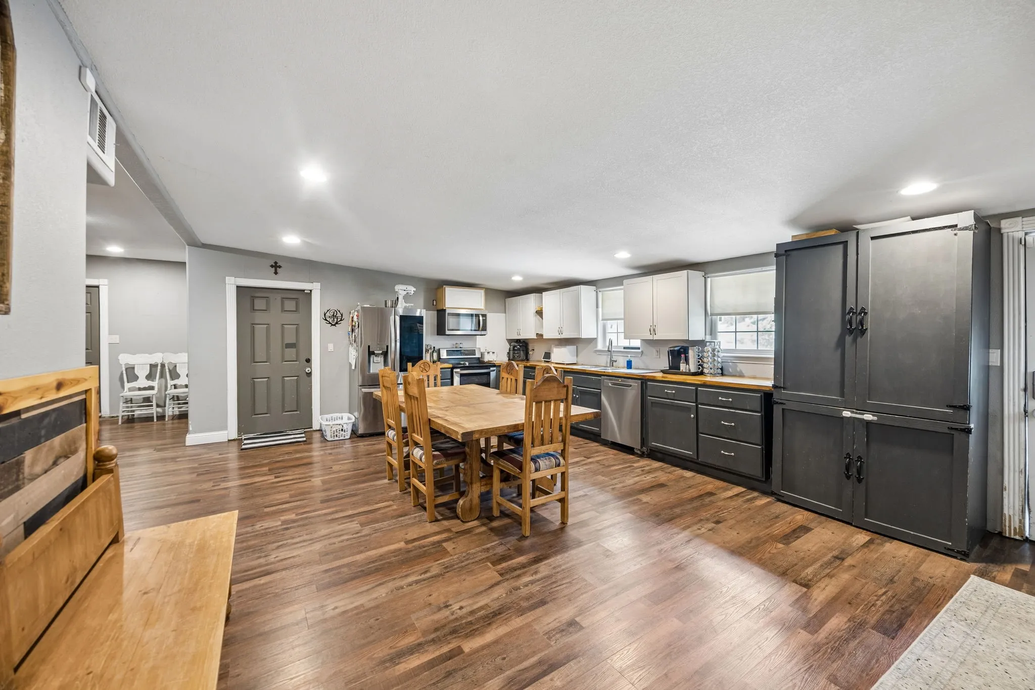 Open-concept kitchen and dining area featuring wood-finish flooring, two-tone cabinetry, stainless steel appliances, and recessed lighting