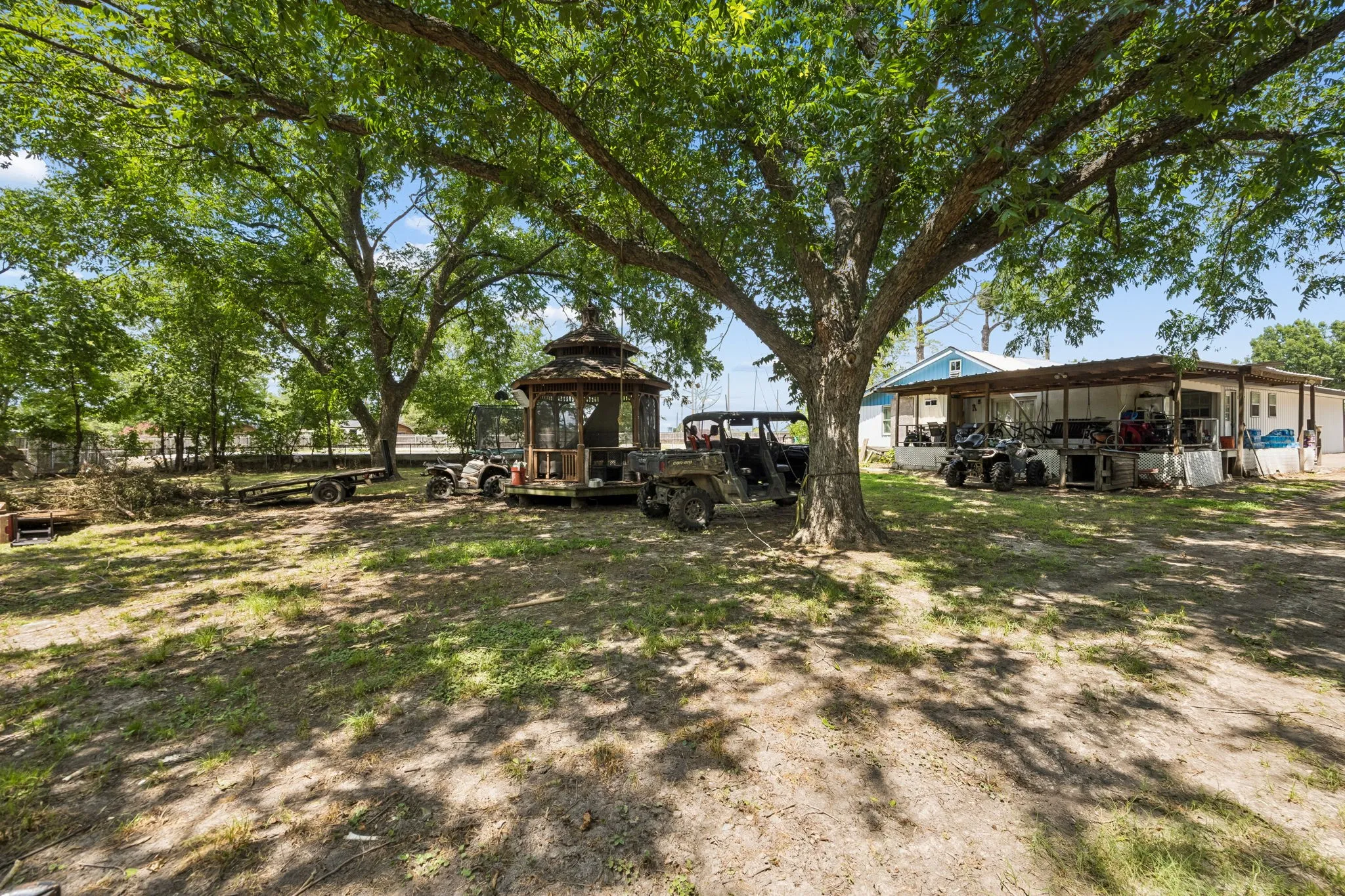 Expansive lot featuring mature shade trees, a wooden gazebo, and a covered porch structure