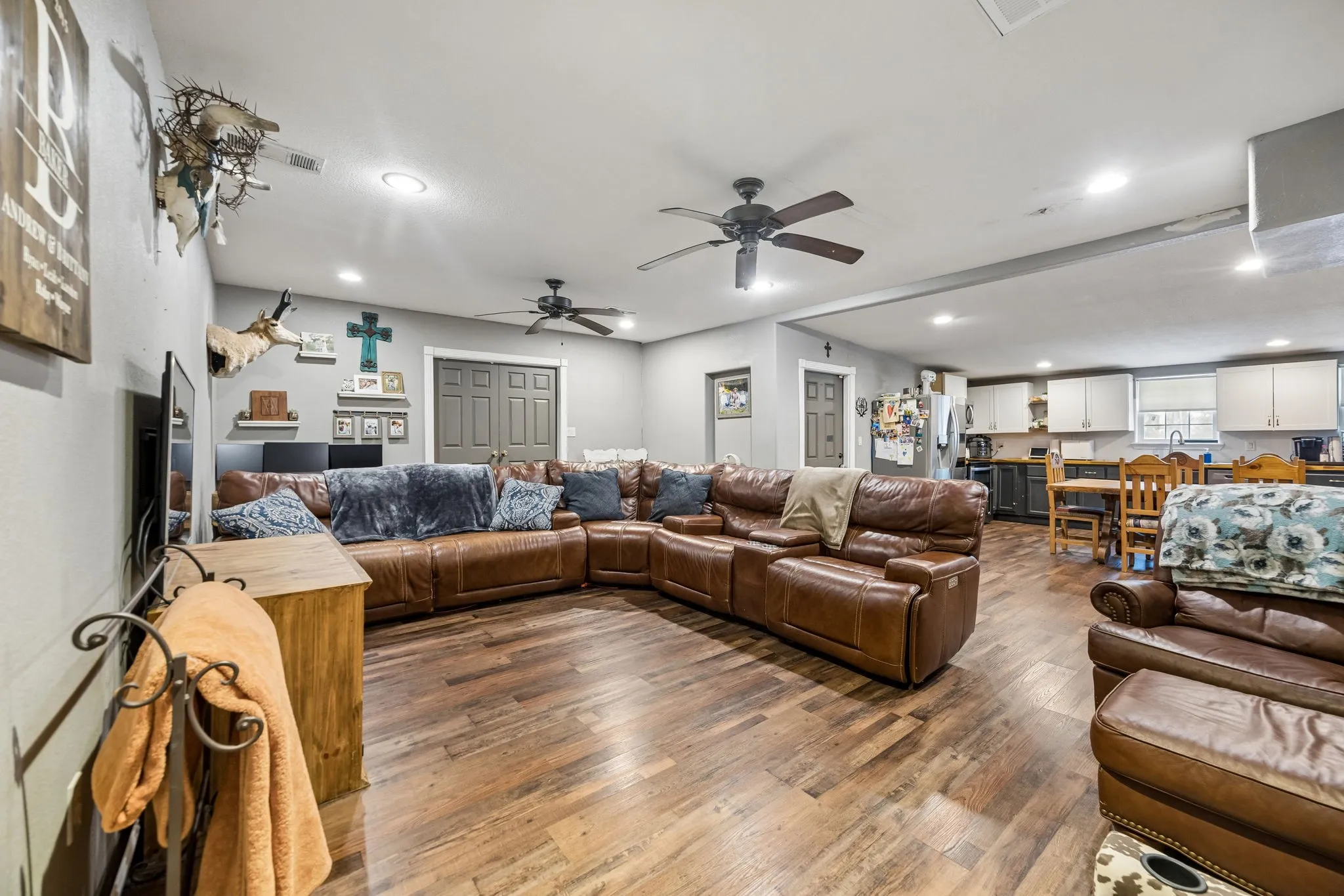 Open-concept living area featuring wood-finish flooring, recessed lighting, and ceiling fans
