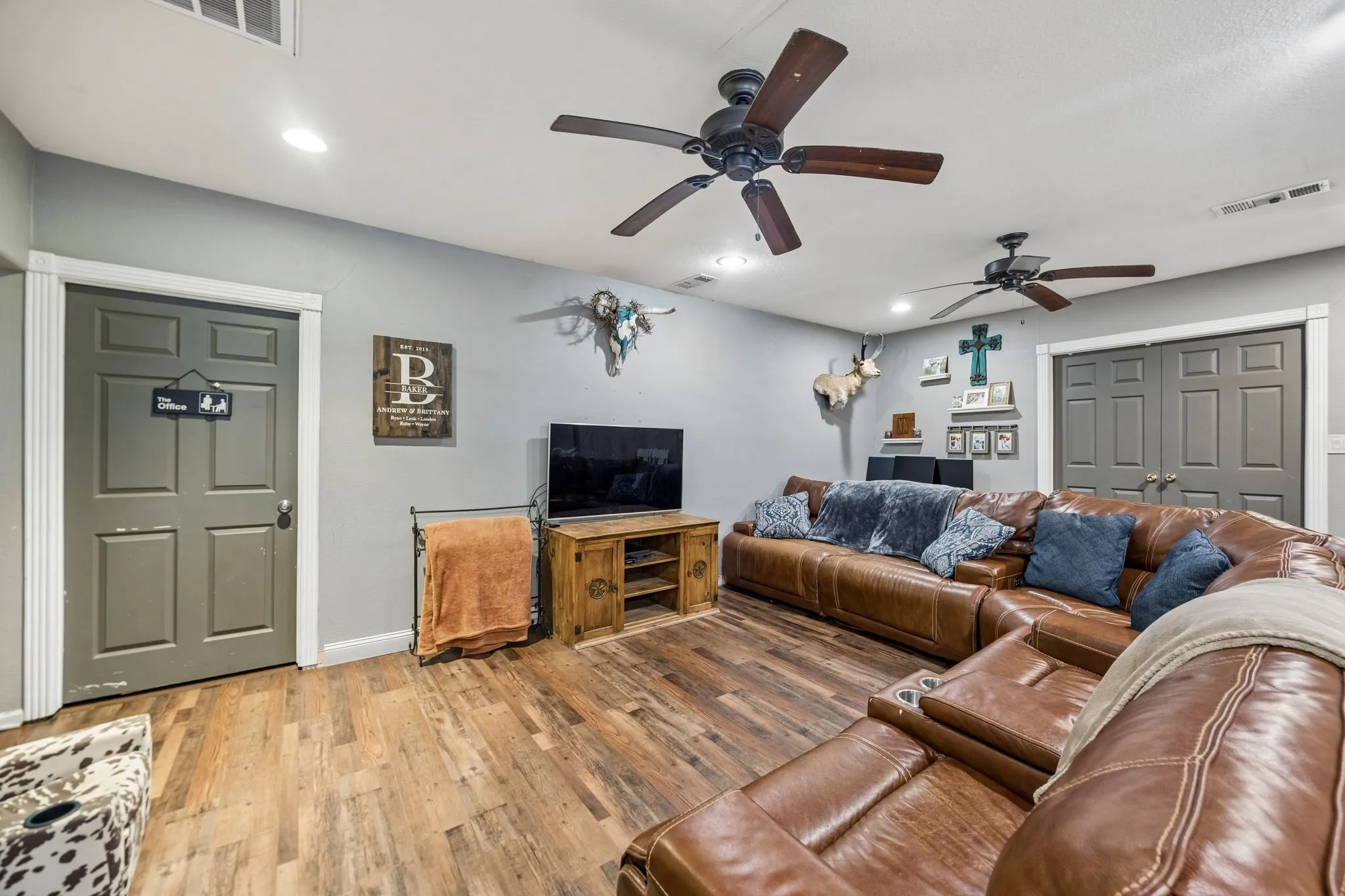 Spacious interior room featuring wood-finish flooring, recessed lighting, and two ceiling fans