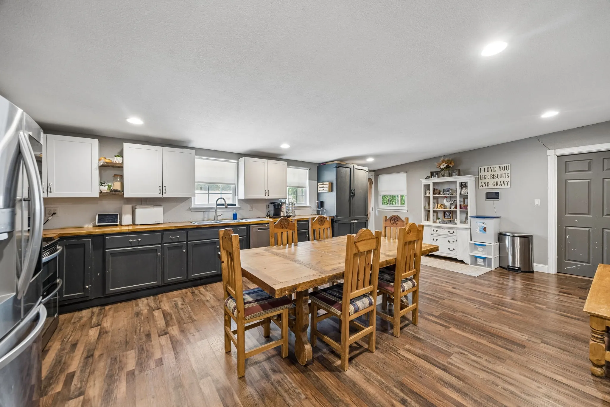 Spacious kitchen featuring wood-finish flooring, two-tone cabinetry with wood-finish countertops, recessed lighting