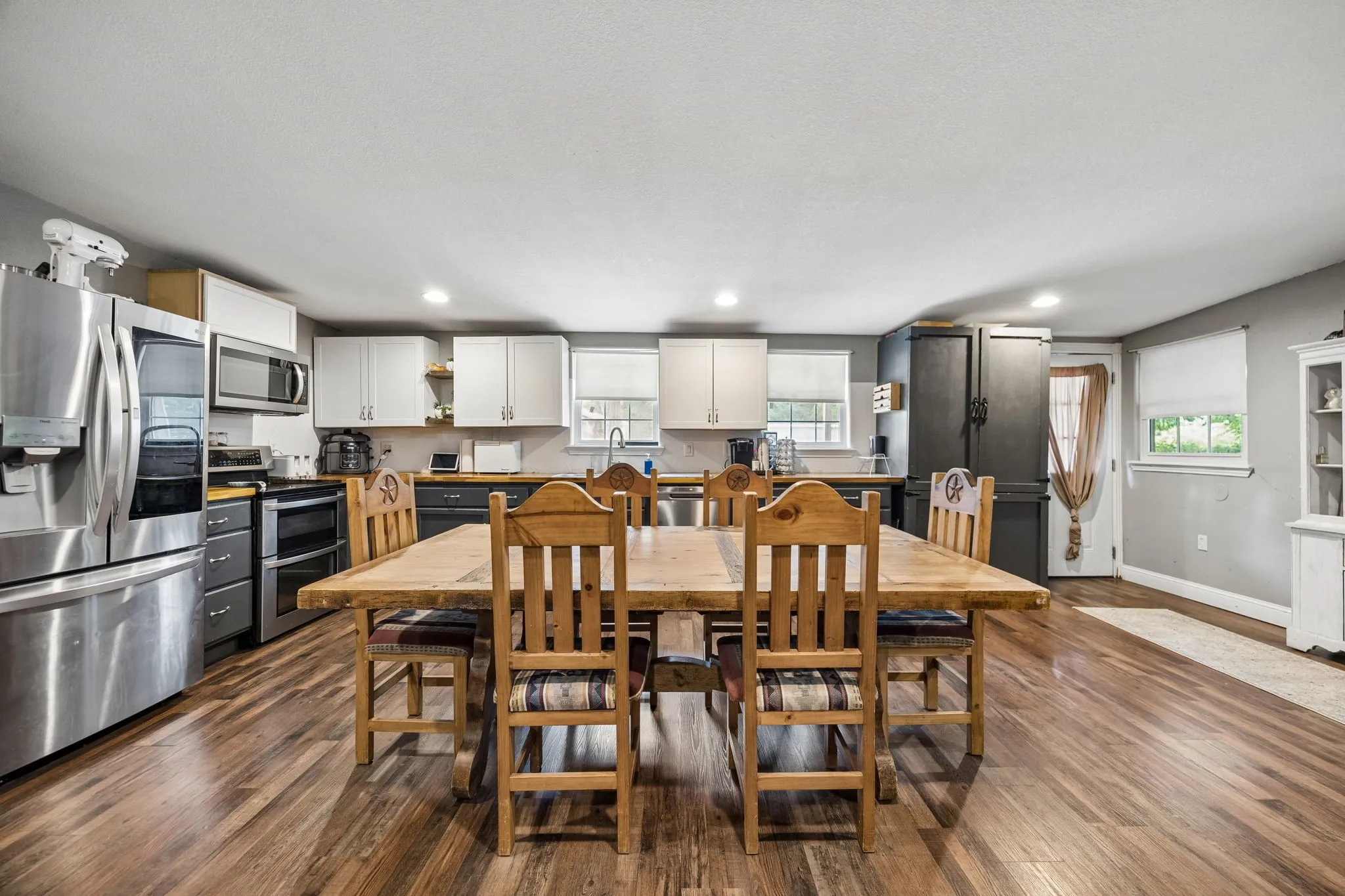 Open-concept kitchen and dining area featuring wood-finish flooring, recessed lighting, and a neutral color palette