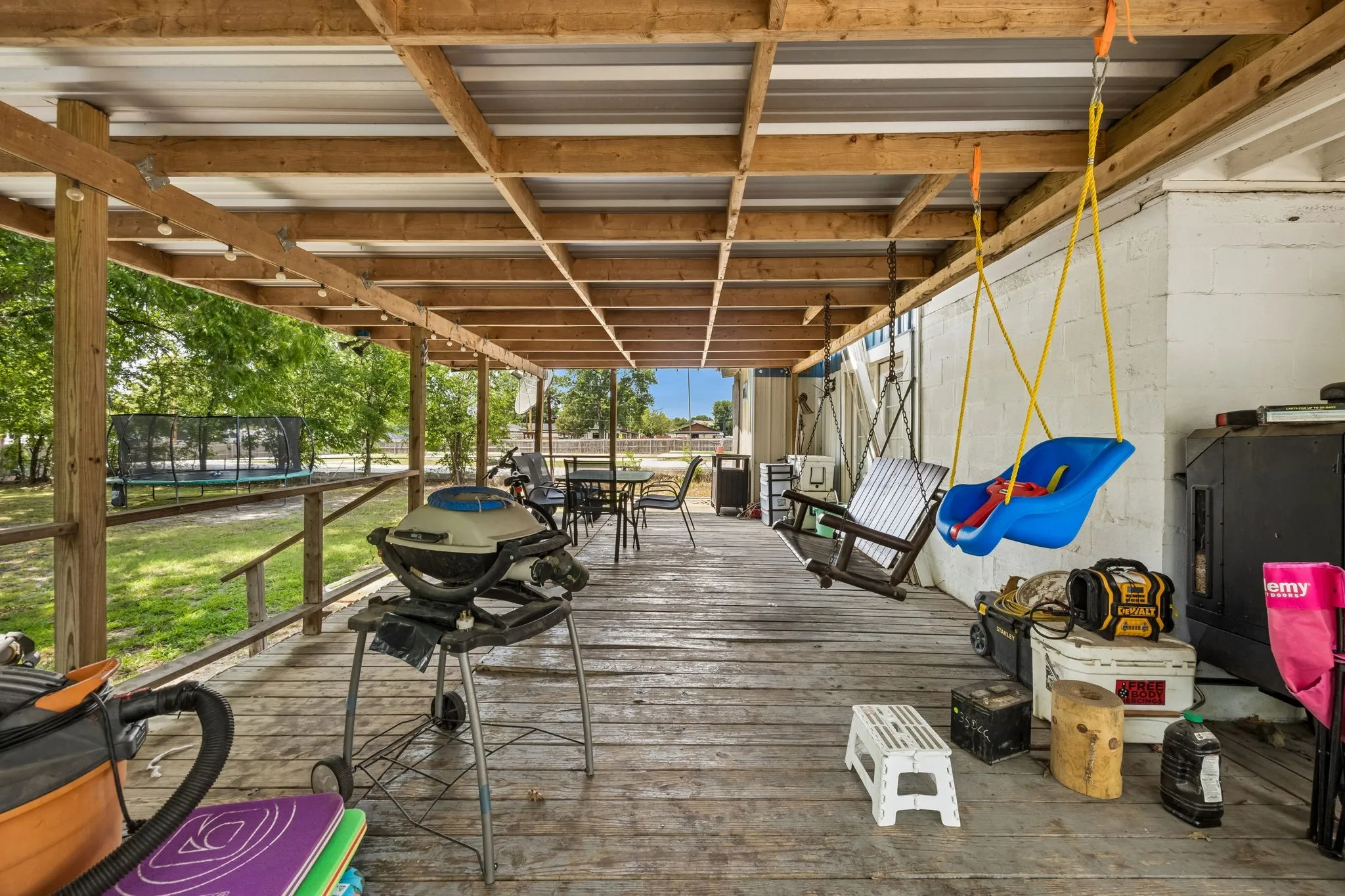 Covered porch featuring wood-finish decking, exposed wood beam ceiling, and string lighting