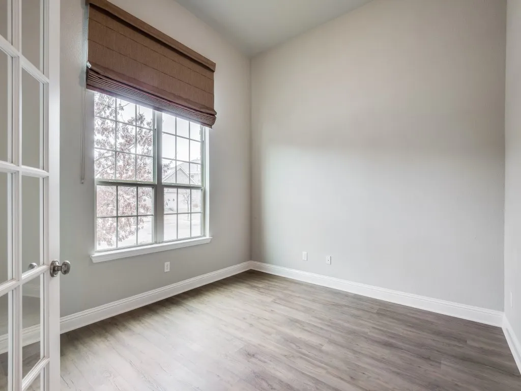 Room featuring French doors, wood-finish flooring, a large window with grid panes, a roman shade, and high ceilings