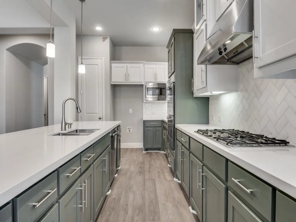 Contemporary kitchen featuring dual-tone cabinetry, light-toned countertops, and wood-finish flooring