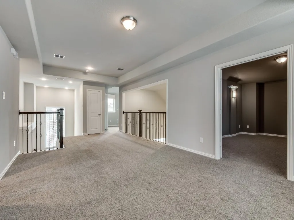 Expansive carpeted loft space featuring light gray walls and recessed lighting