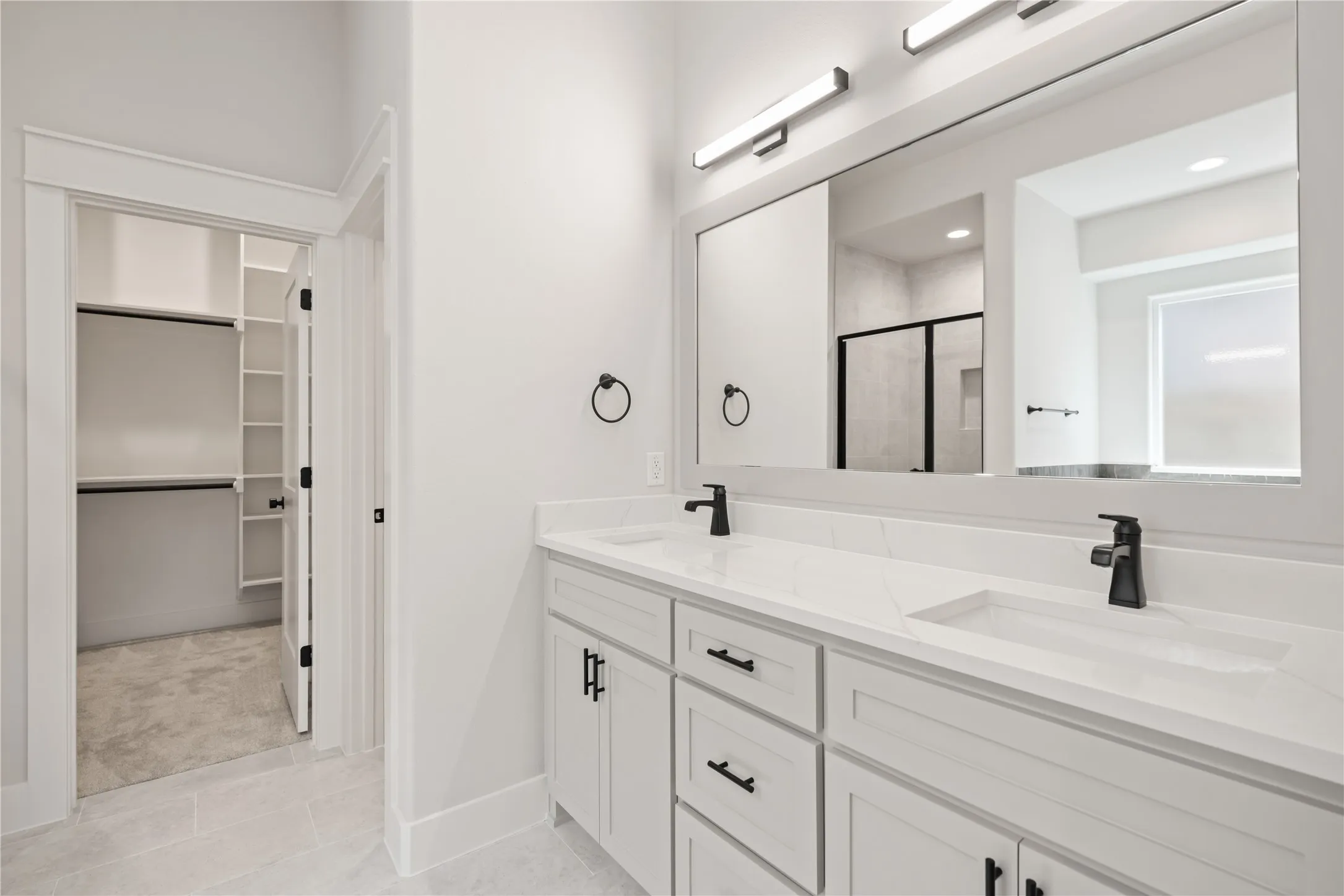 Dual vanity with integrated sinks, white cabinetry, and matte black hardware