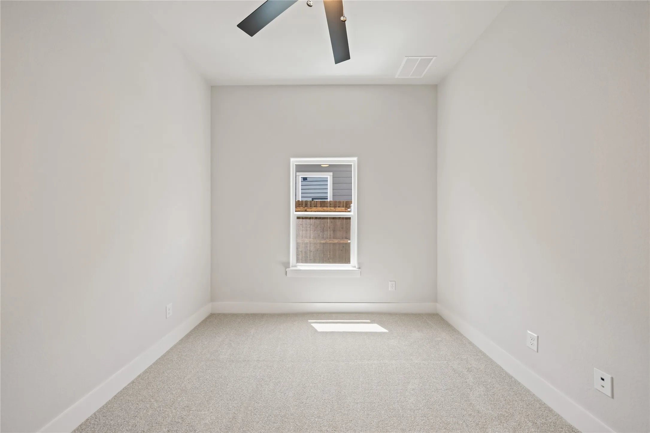 Carpeted interior space featuring a single window and a ceiling fan with integrated lighting