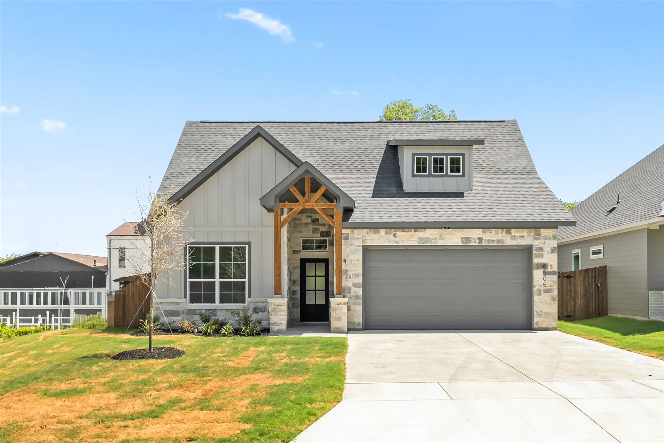 Contemporary home exterior featuring board-and-batten siding, stone facade, a gabled roof, and a prominent wood-beam porch accent