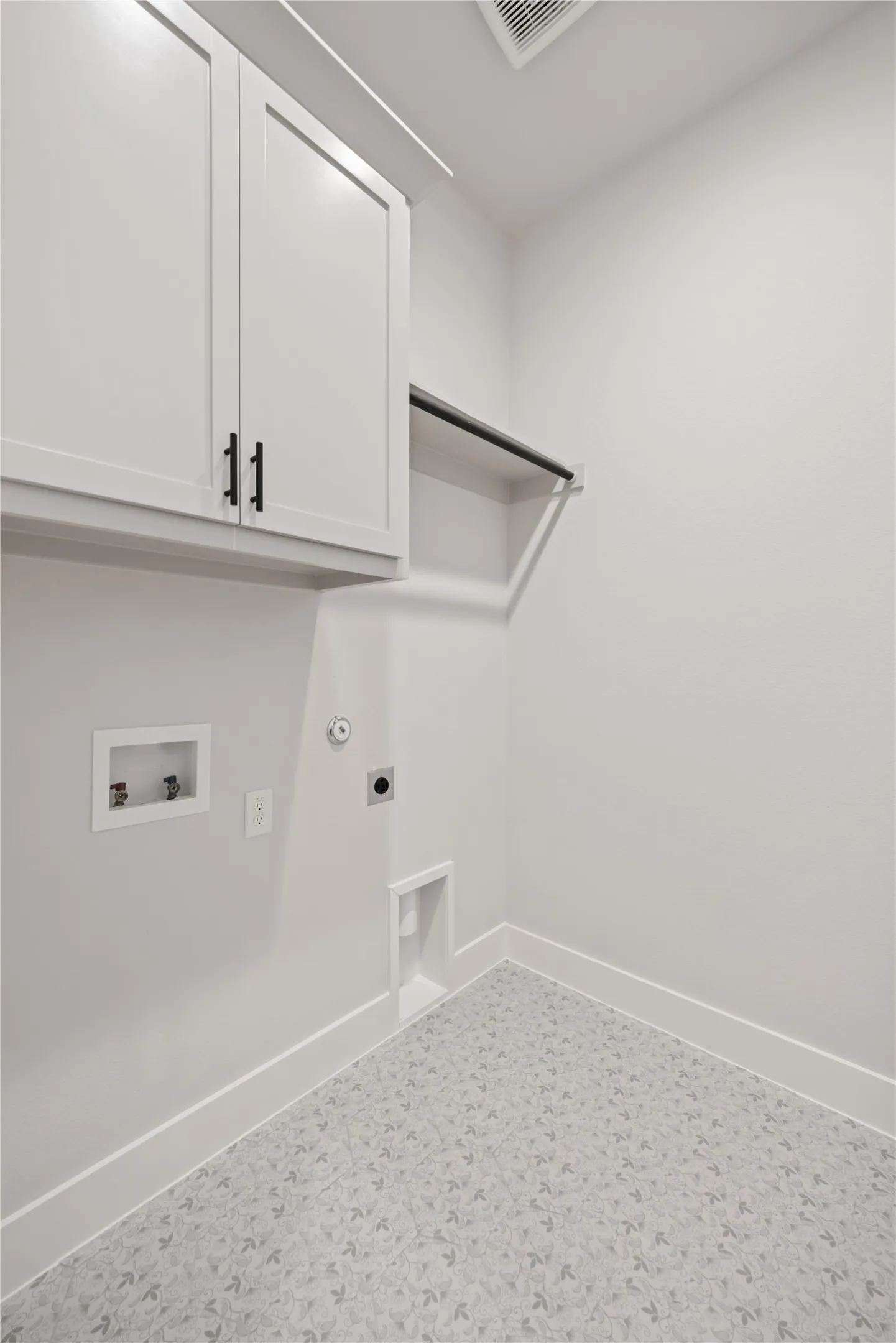 Dedicated laundry area featuring white shaker-style cabinetry with matte black hardware