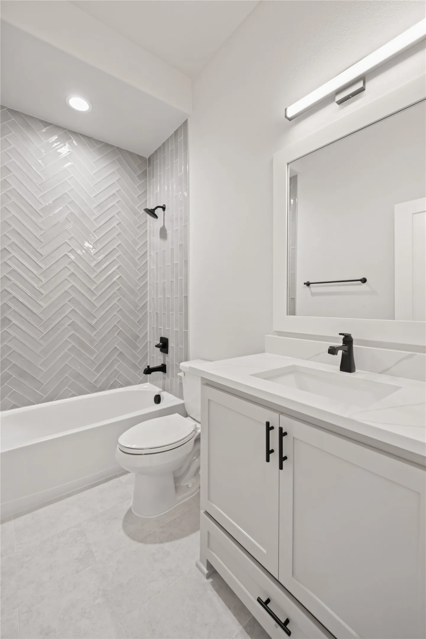 Contemporary bathroom featuring a white vanity with matte black hardware, an integrated sink, and a white countertop