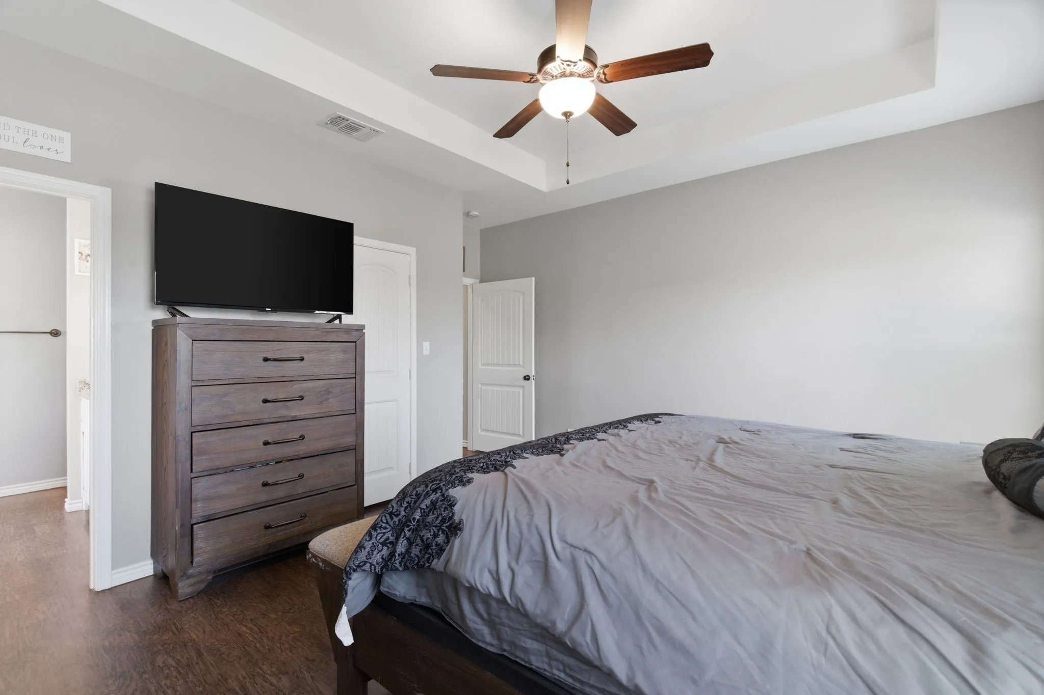 Bedroom featuring a raised ceiling, ceiling fan, and dark wood-style flooring
