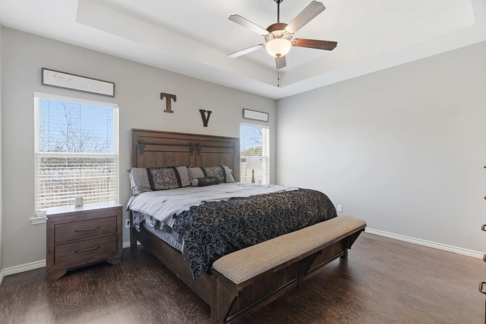 Bedroom featuring a tray ceiling, dark wood-style flooring, and ceiling fan