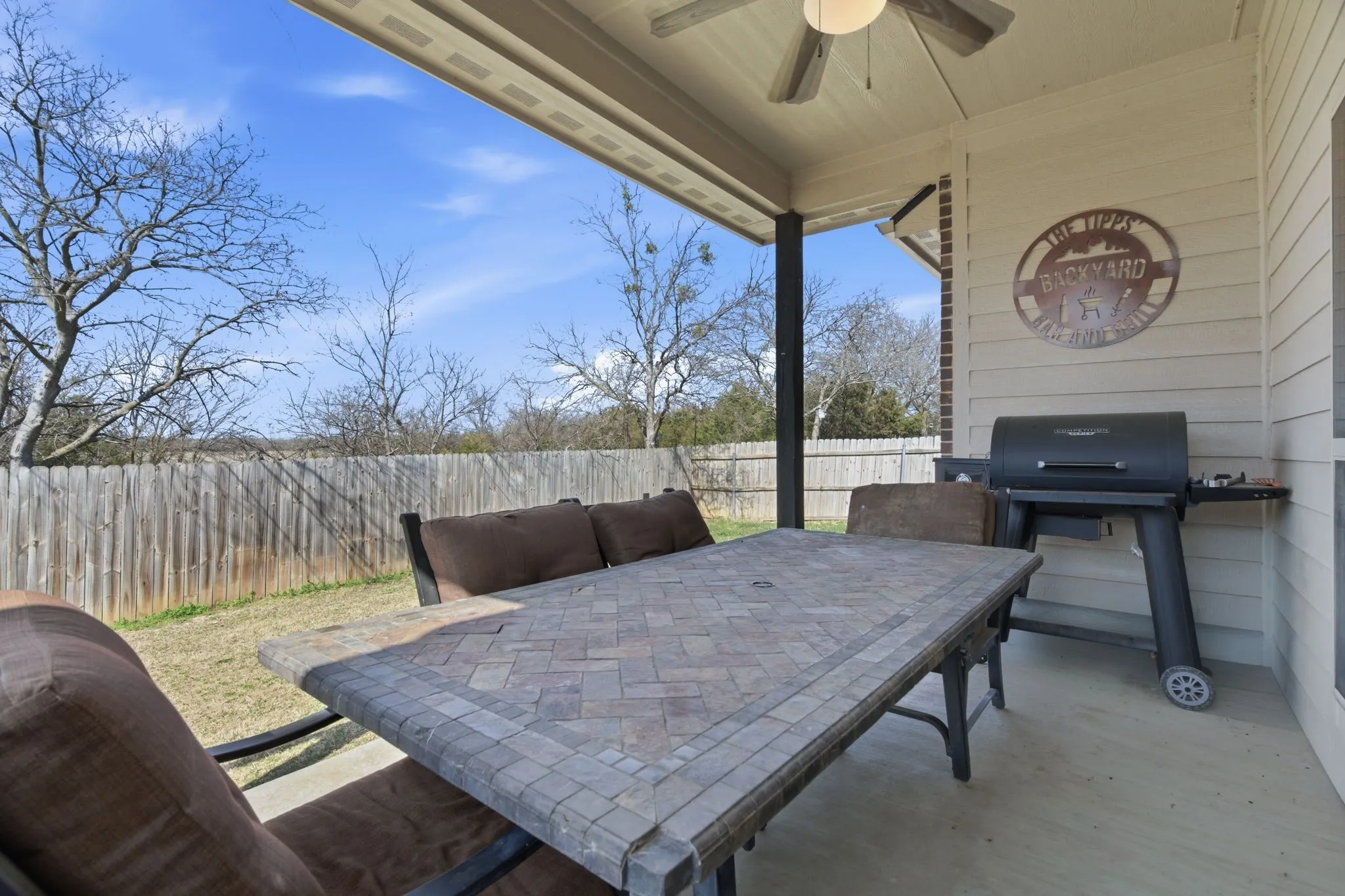 Fenced backyard with a patio, ceiling fan, a grill, and outdoor dining area