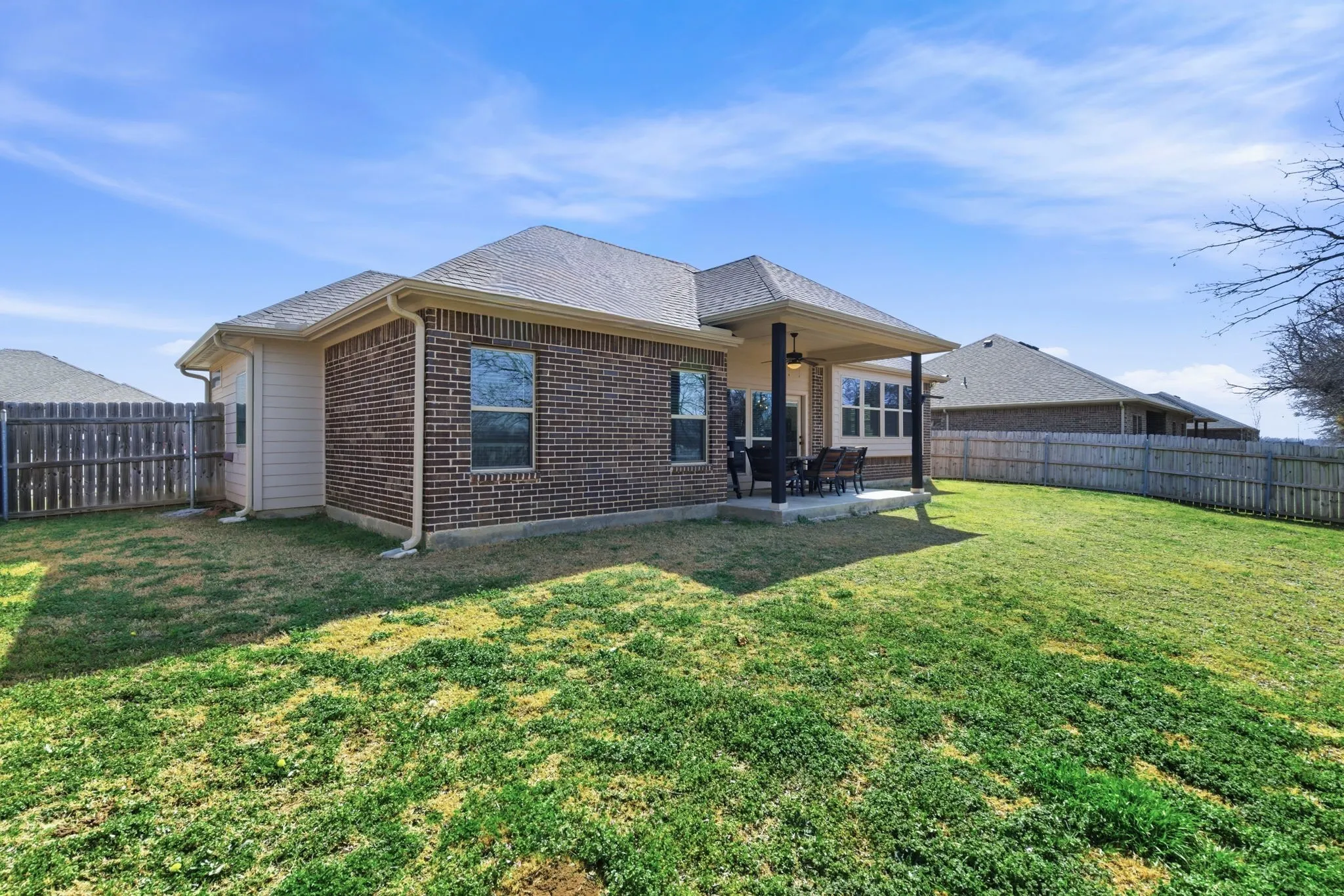 Back of house featuring a fenced backyard, a patio area, brick siding, and roof with shingles