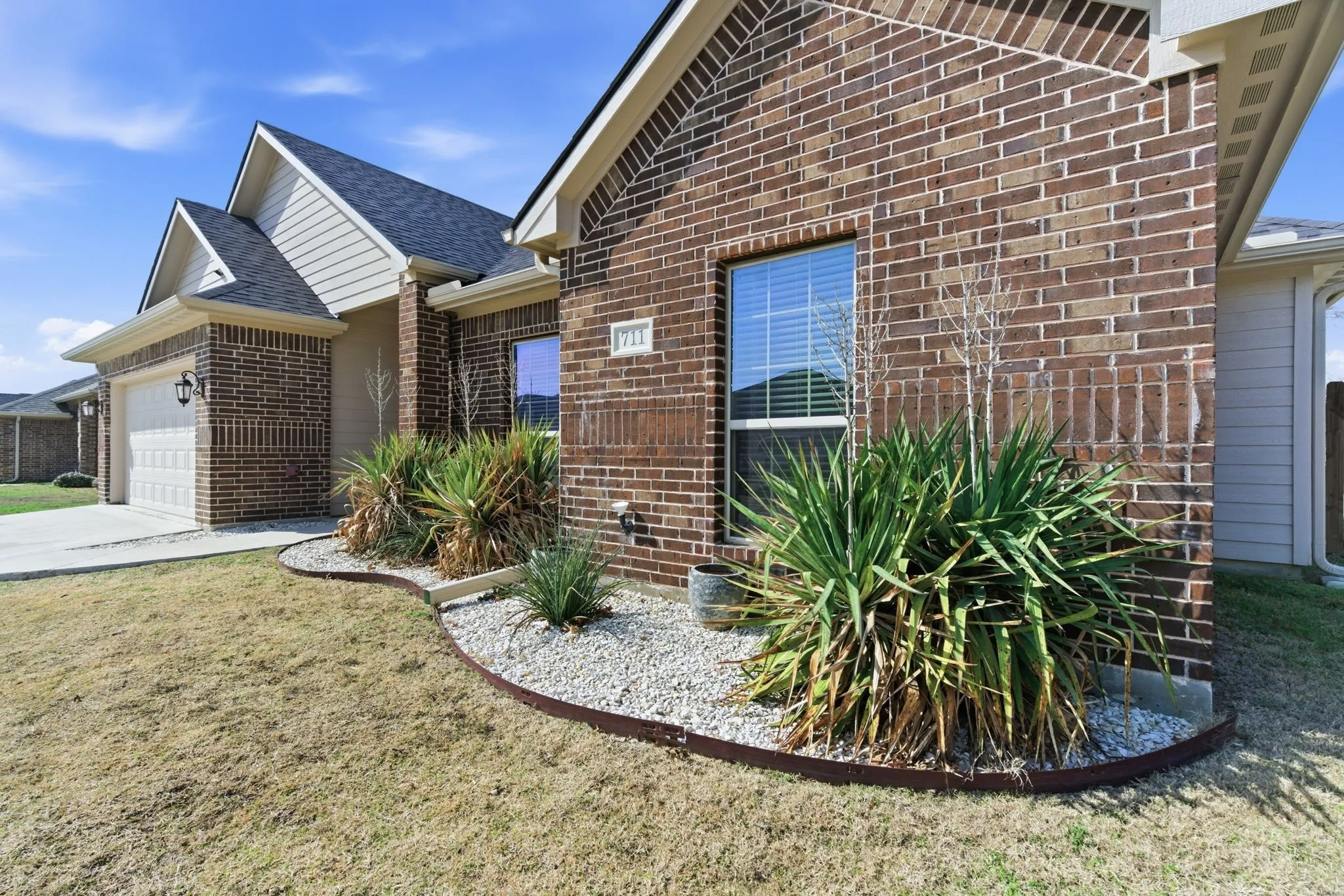 View of home's exterior with brick siding, an attached garage, a yard, roof with shingles, and concrete driveway