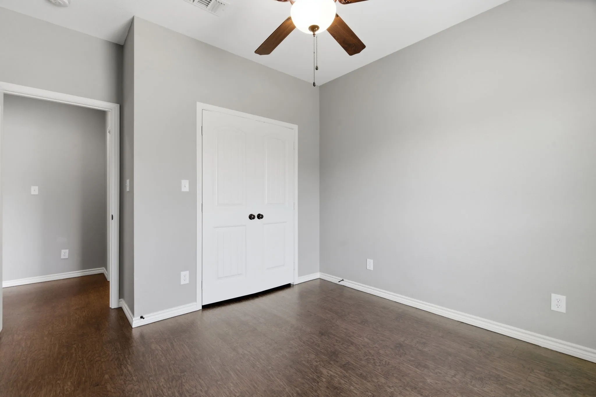 Unfurnished bedroom featuring a closet, dark wood-style flooring, and ceiling fan