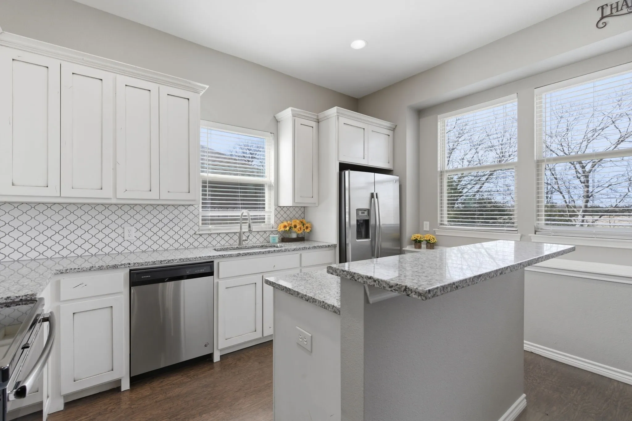 Kitchen with white cabinetry, dark wood-type flooring, stainless steel appliances, tasteful backsplash, and a kitchen island