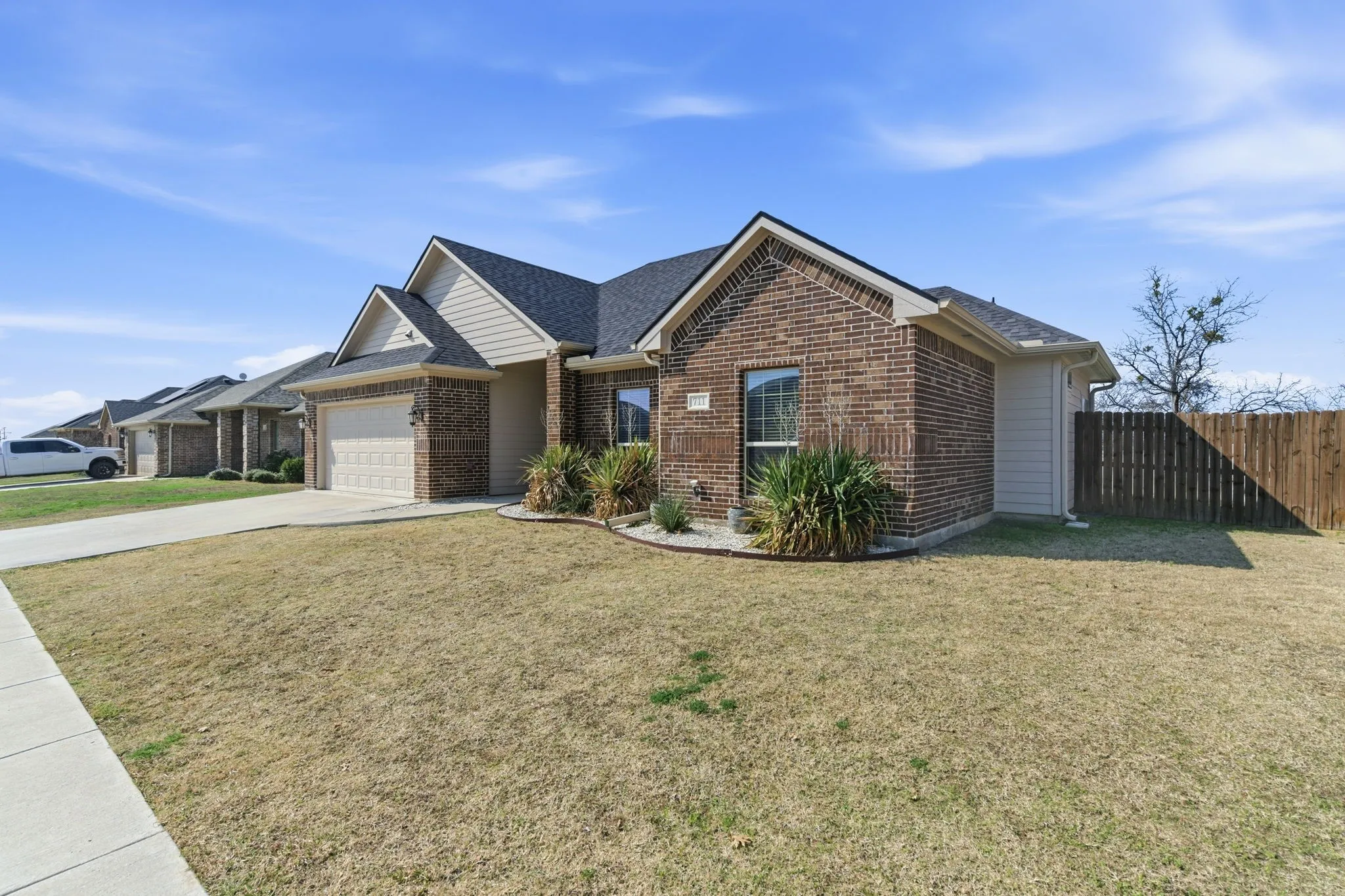 Ranch-style home featuring brick siding, an attached garage, concrete driveway, and roof with shingles