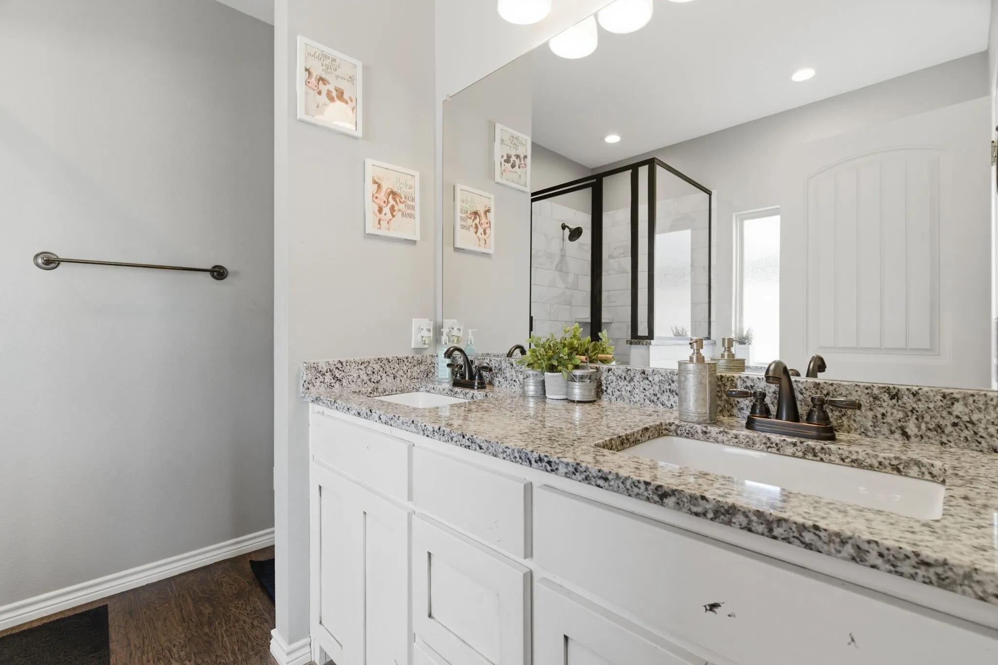 Bathroom with a stall shower, double vanity, and dark wood finished floors