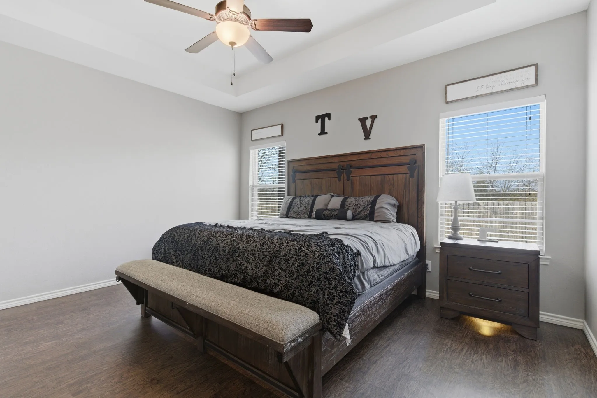Bedroom featuring dark wood-type flooring, a ceiling fan, and a tray ceiling