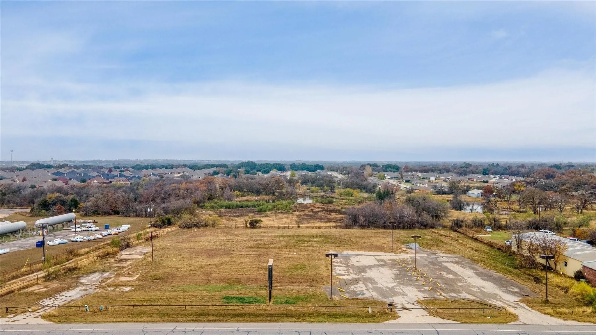 Expansive undeveloped land featuring a cleared lot, paved parking area, and street frontage