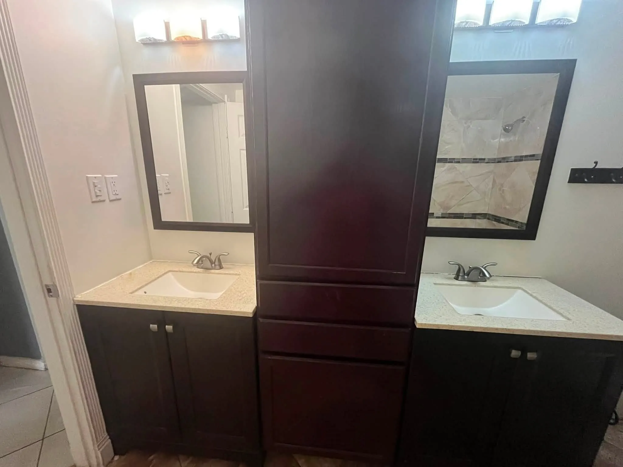 Dual dark wood vanities featuring integrated white sinks and light-toned countertops