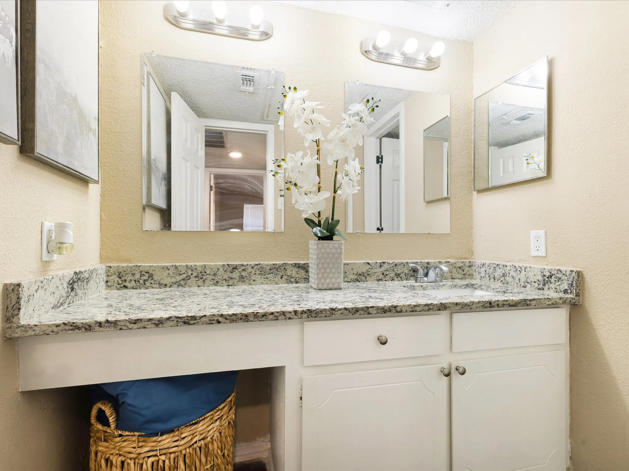 Double vanity featuring a light-toned countertop, dual mirrors, and white cabinetry