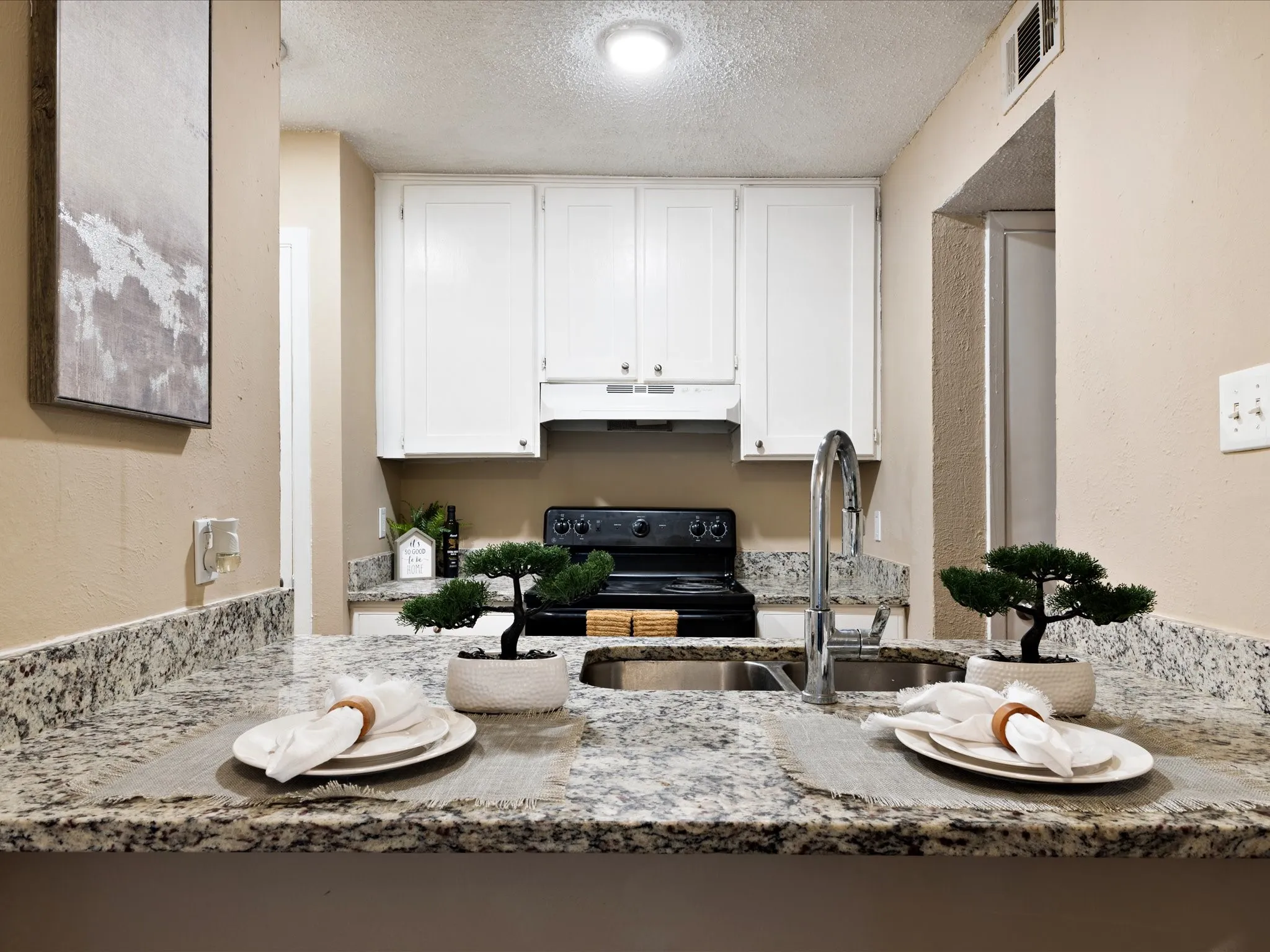 Kitchen featuring granite countertops, white cabinetry, a stainless steel sink with a high-arc faucet, and black appliances