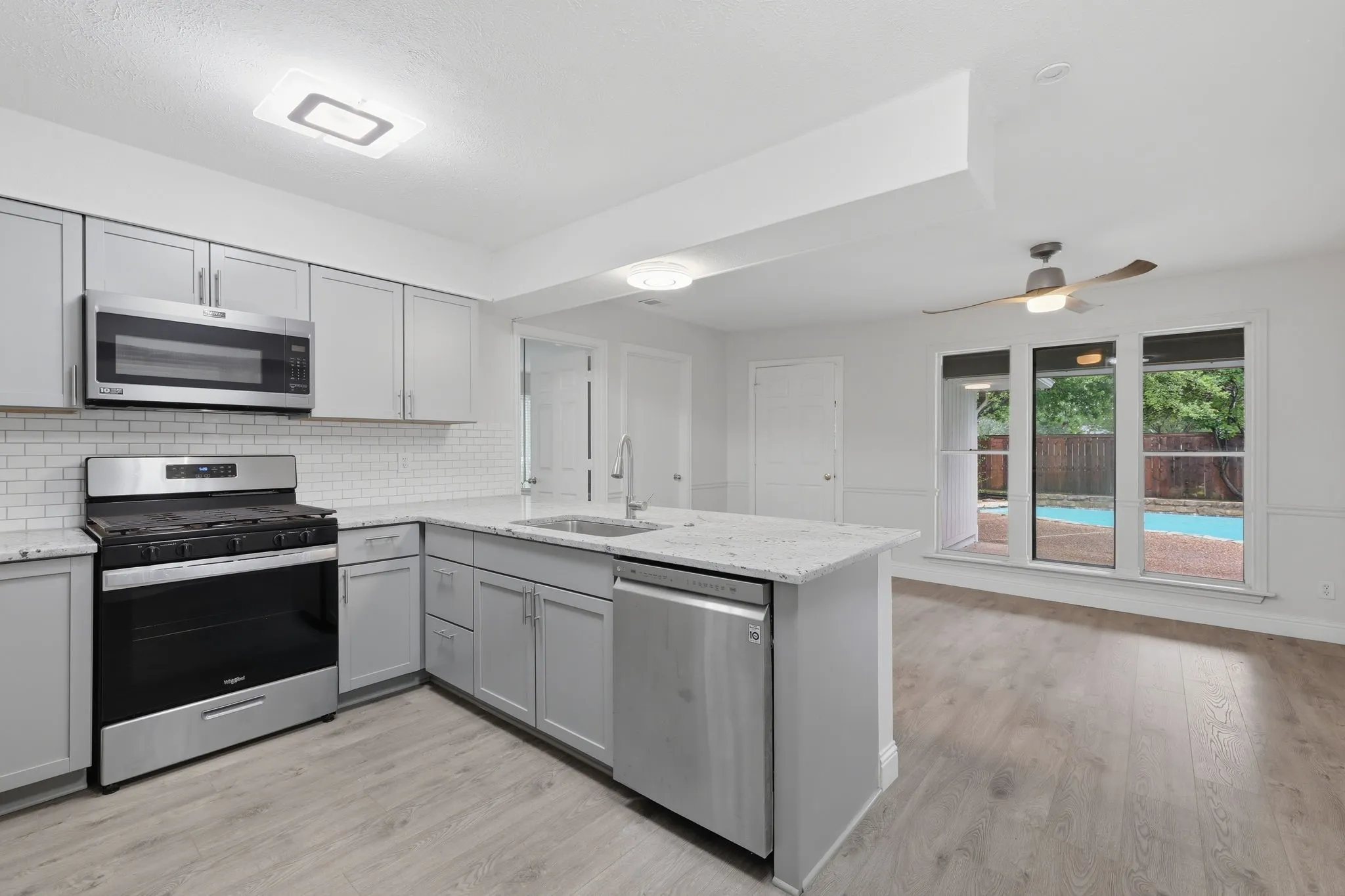 Kitchen featuring light gray cabinetry, stainless steel appliances, and white subway tile backsplash