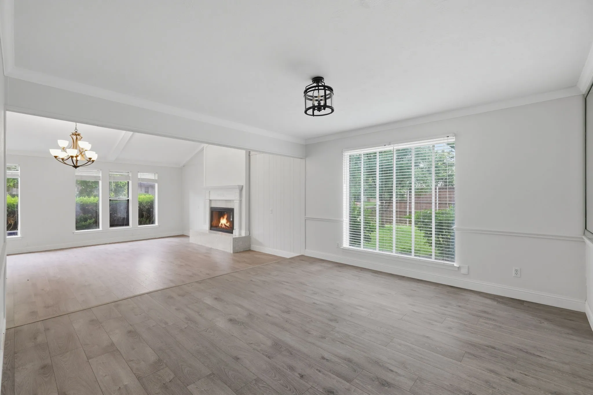 Bright interior featuring wood-finish flooring, a fireplace with a tiled hearth, and large windows with horizontal blinds