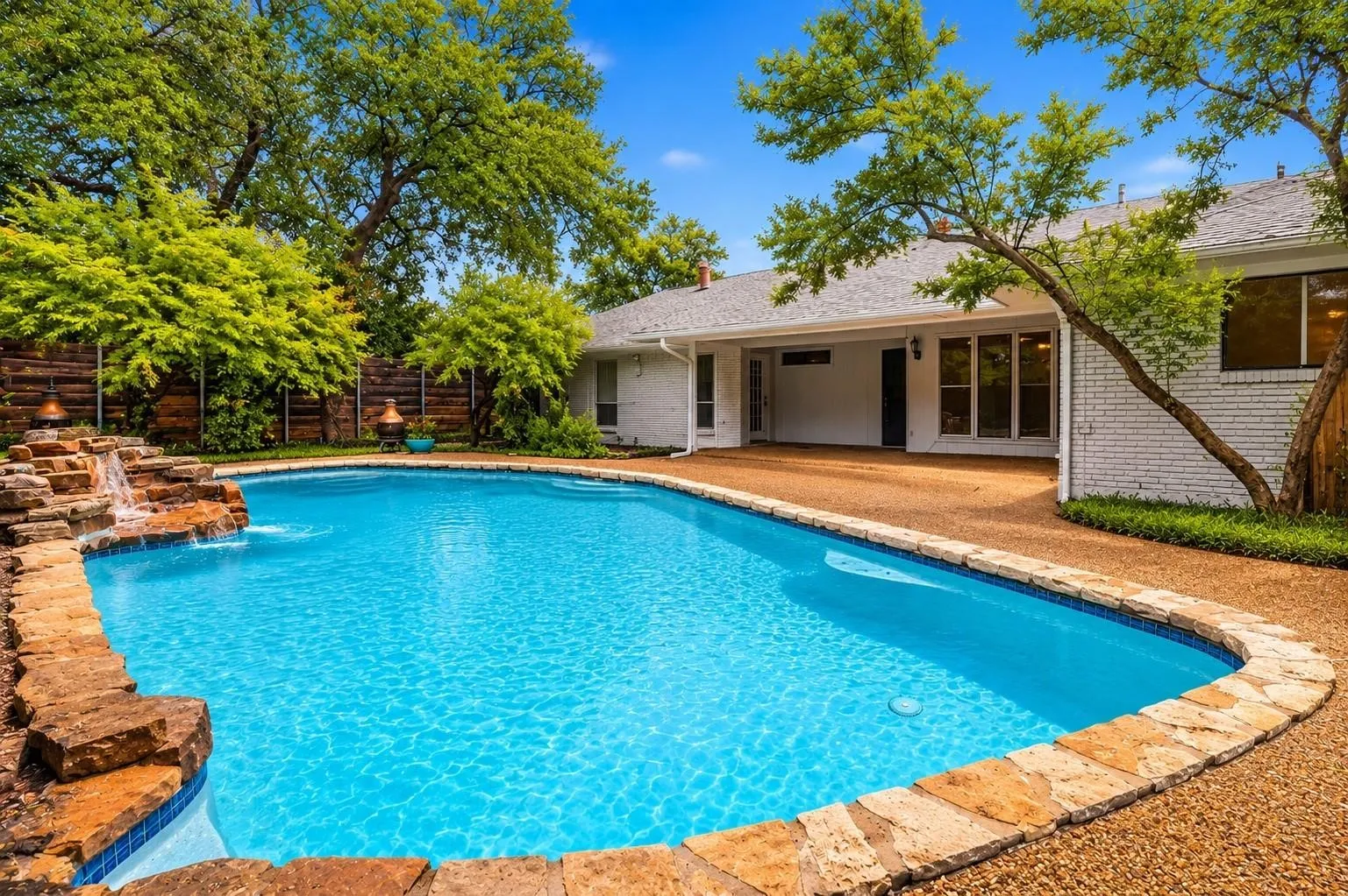 Outdoor oasis featuring a custom swimming pool with a rock waterfall
