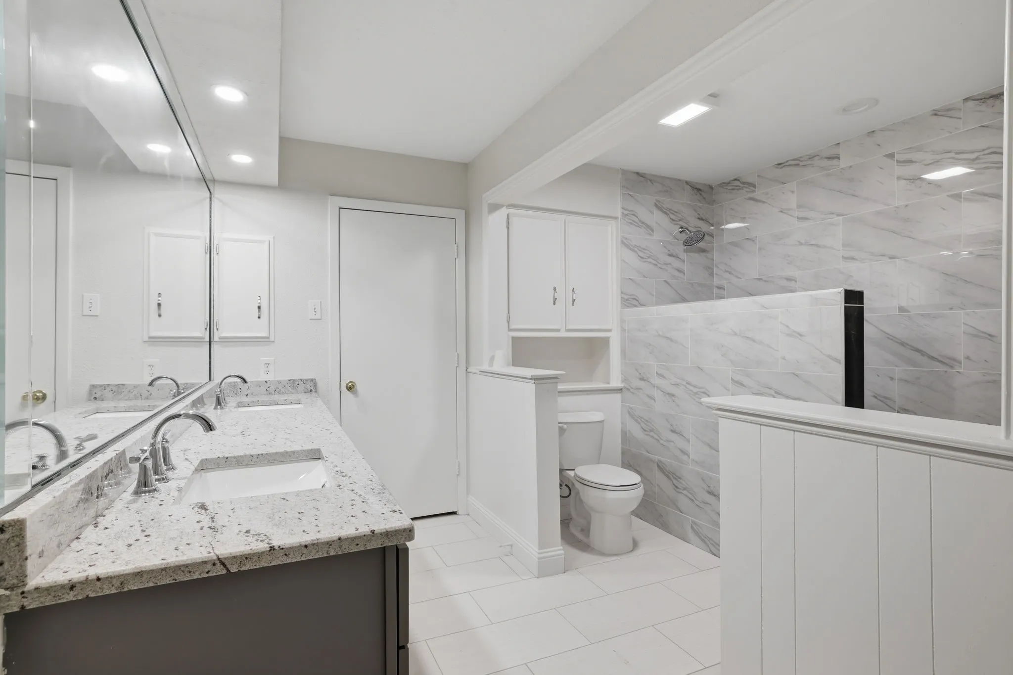 Bathroom featuring a dual vanity with a speckled countertop, undermount sinks, and chrome faucets