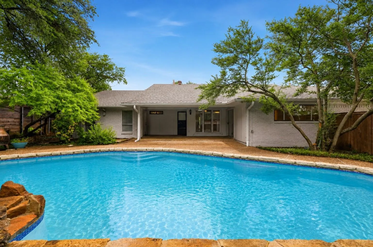 Backyard featuring a rectangular swimming pool with integrated rock features and tile accents