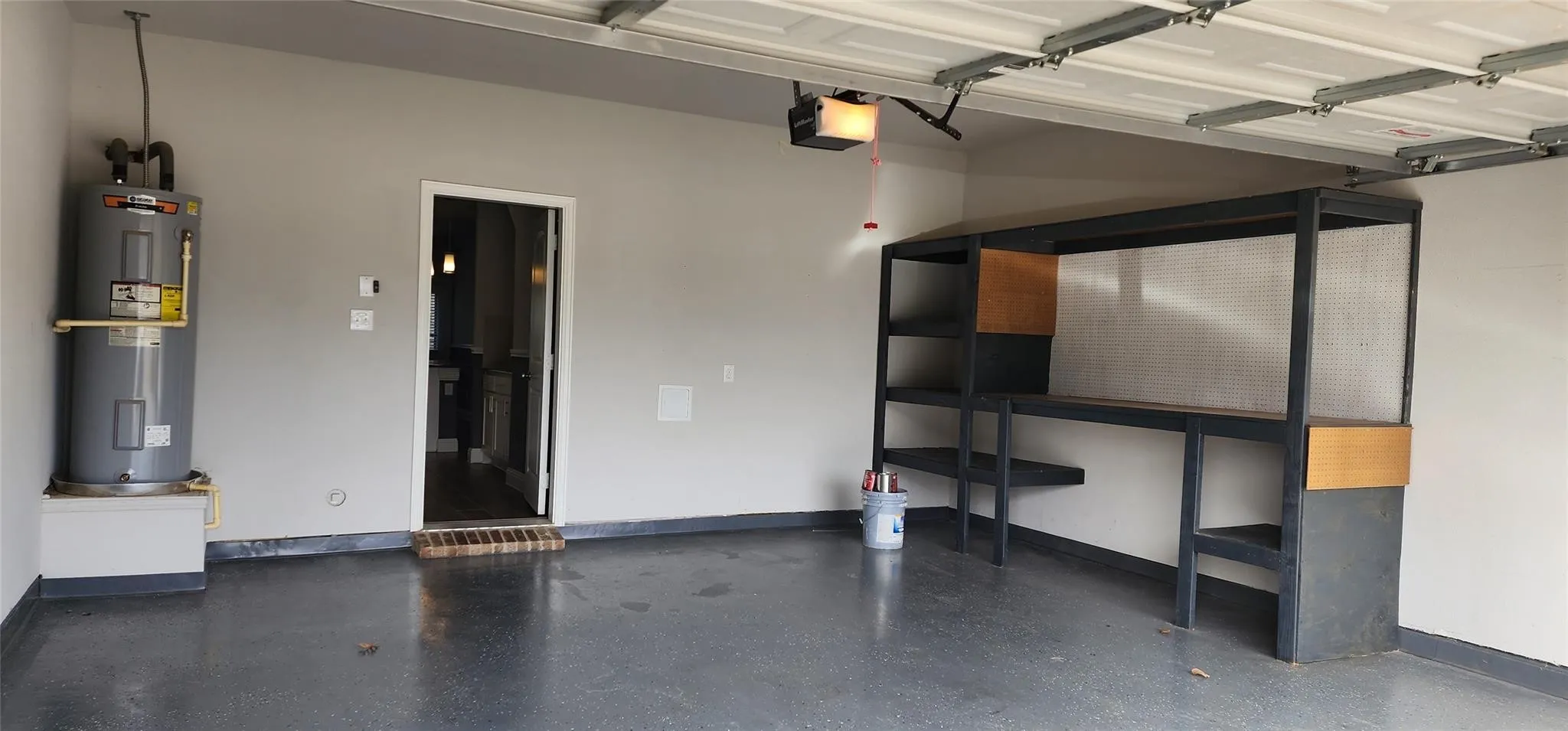 Two-car garage featuring a gray epoxy floor, built-in shelving, and a workshop area with wood-finish accents