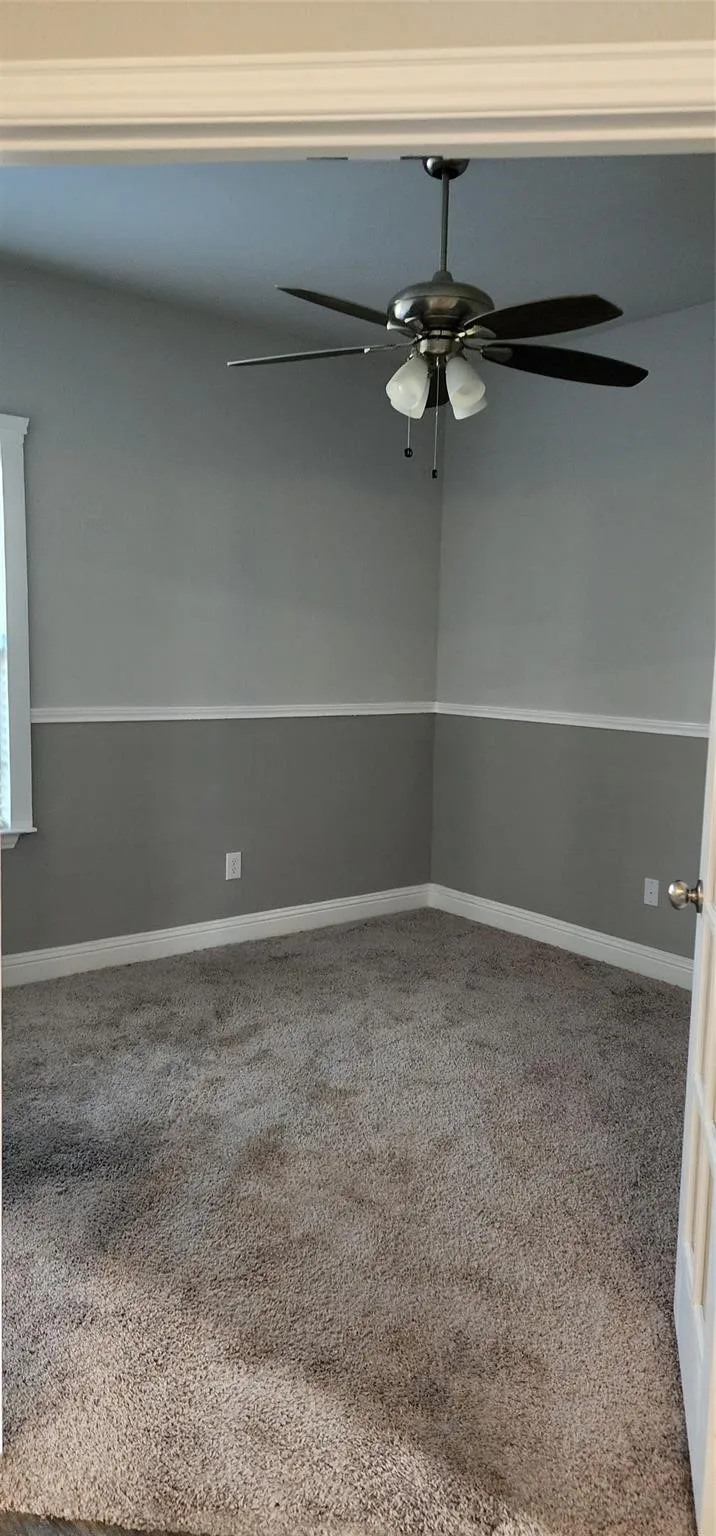 Interior room featuring two-tone walls with a chair rail, a ceiling fan with integrated lighting, and neutral carpet flooring